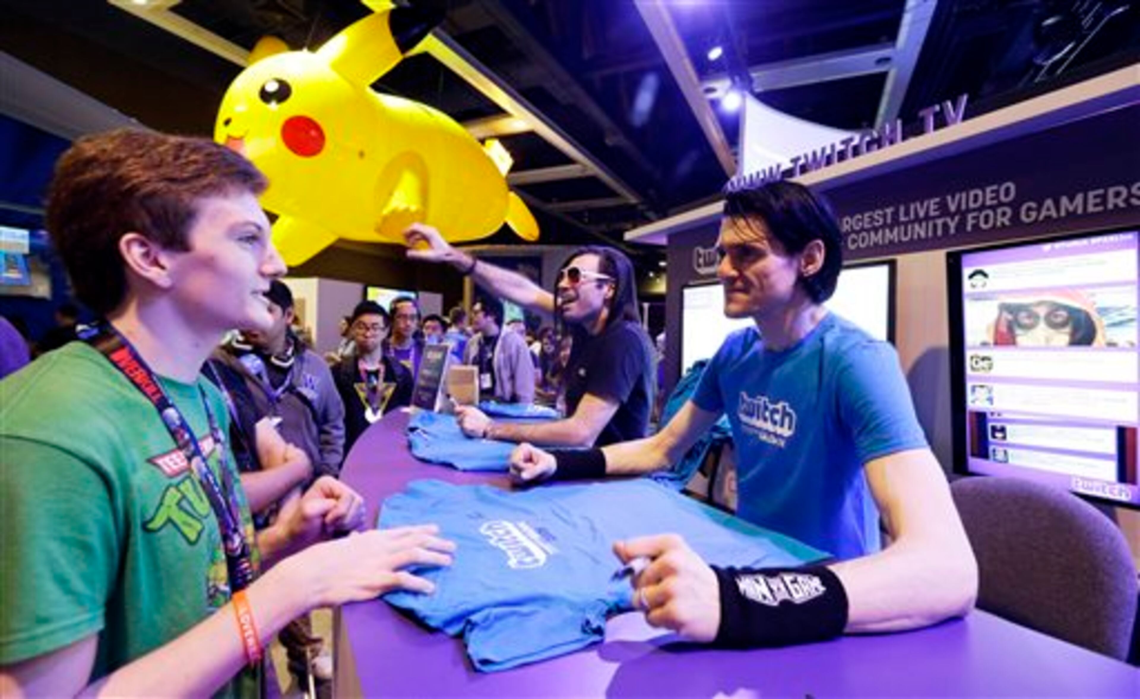 A fan gets an autograph from Jason "MANvsGAME" Love, right, as Love sits with Justin "TheJustinFlynn" Flynn, second from right, at the booth for the online video game community "Twitch," Friday, Aug. 29, 2014, at the Penny Arcade Expo, a fan-centric celebration of gaming in Seattle. Both men host programs and gaming seminars on the online network. (AP Photo/Ted S. Warren)