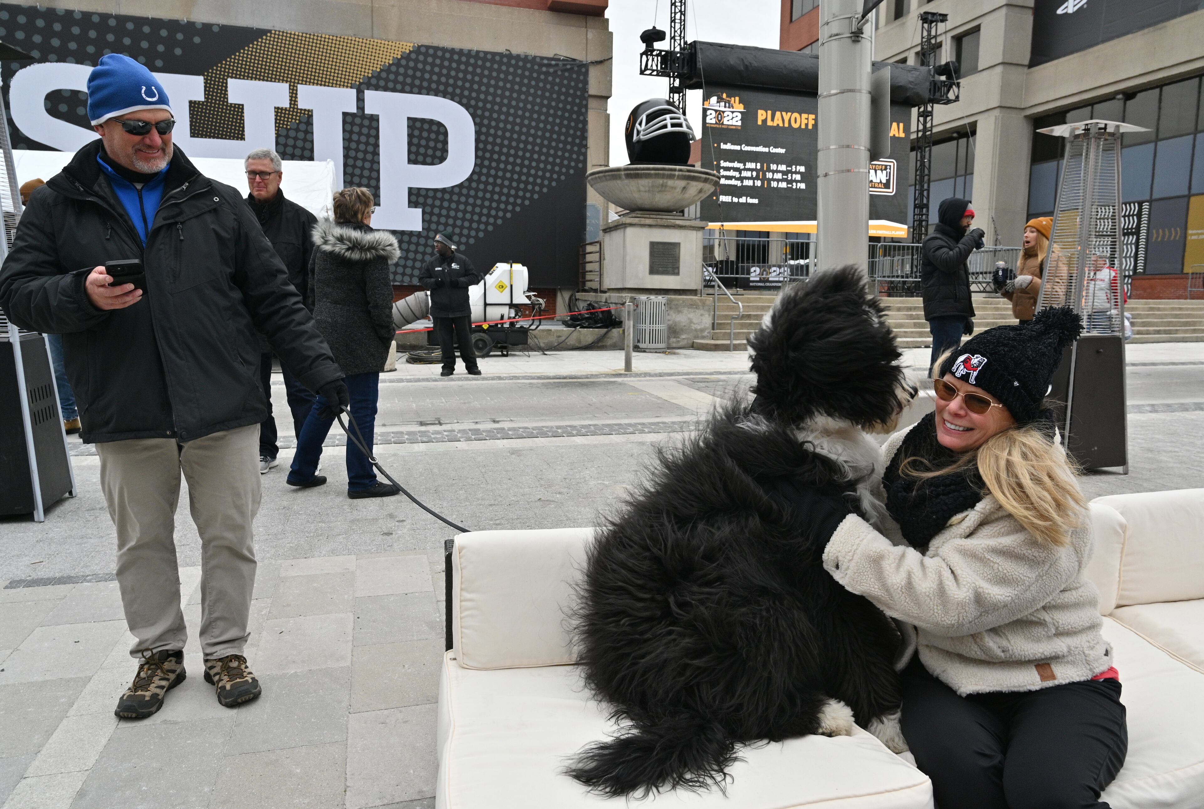 Georgia fan Jodi Hart plays with a dog as she enjoys live music on Georgia Street in downtown Indianapolis on Saturday, January 8, 2022. 2022 College Football Playoff National Championship culminates in a weekend of events as downtown Indianapolis transforms into Championship Campus. Festival of attractions and activities starting Saturday, January 8 through Monday, January 10. (Hyosub Shin / Hyosub.Shin@ajc.com)