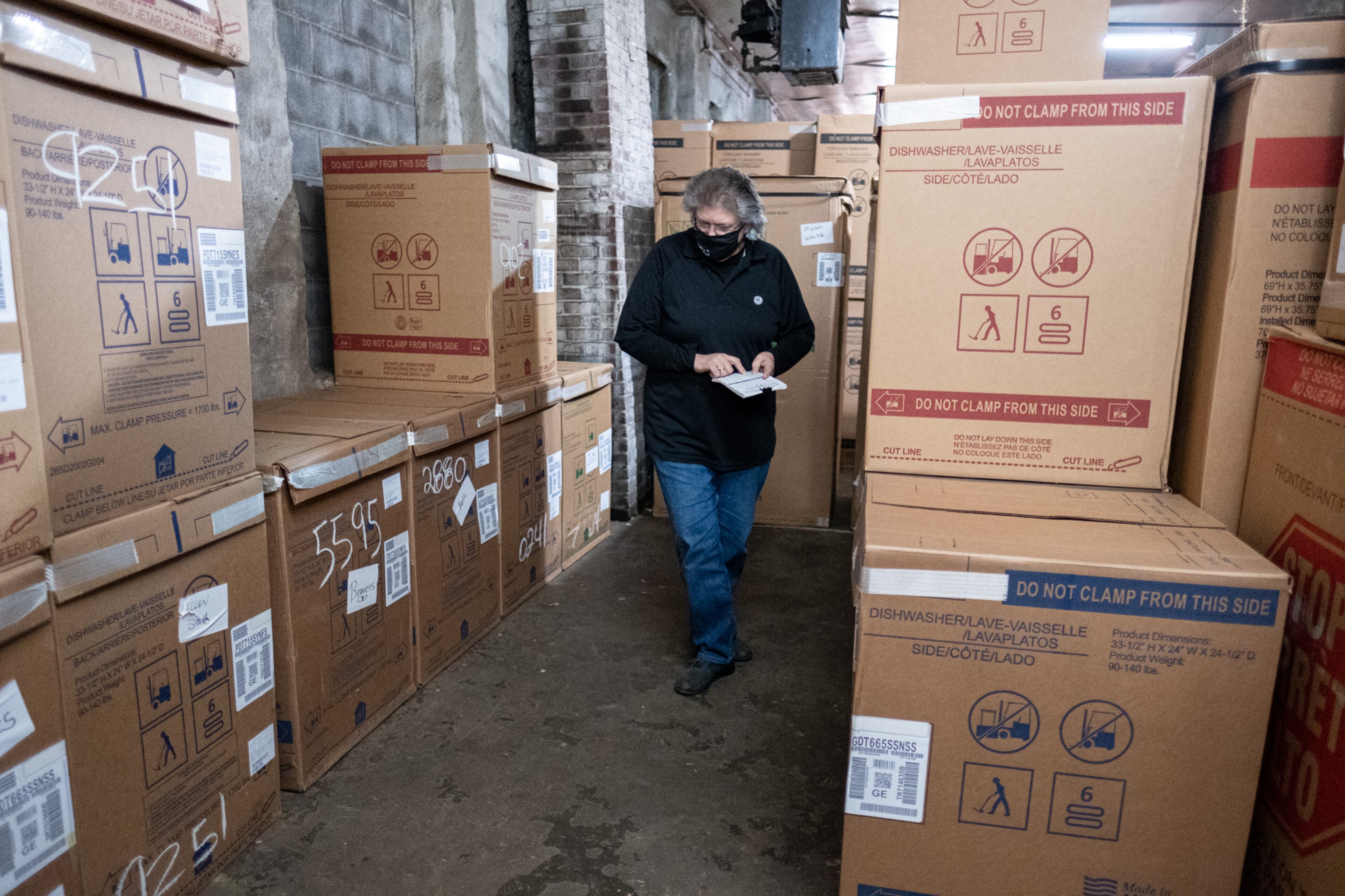 201105-Douglasville-Vickie Mitchell, co-owner of Mitchell Appliance Company in Douglasville, looks for a customer’s order in store’s warehouse Thursday afternoon, Nov 5, 2020. Normally the dishwashers would be stacked three high, but Mitchell said she is having a hard time getting appliances because the pandemic has slowed manufacturing. Ben Gray for the Atlanta Journal-Constitution