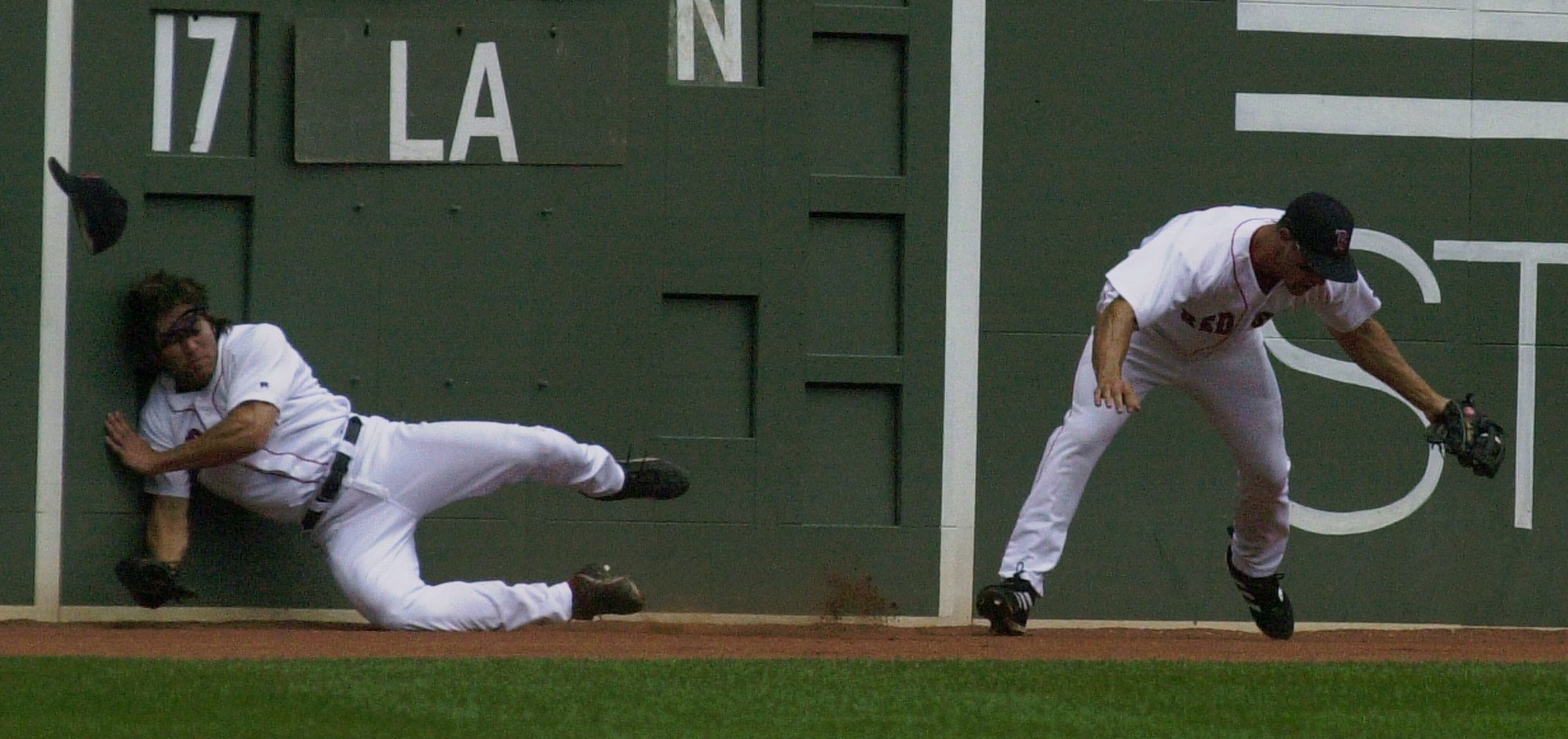 Red Sox center fielder Johnny Damon, left, slams against the outfield wall after colliding with left fielder Gabe Kapler, right, who caught the pop-fly hit by New York Yankees' Bernie Williams in the third inning of their Saturday, Aug. 30, 2003, game. (AP Photo/Olivia Nisbet)