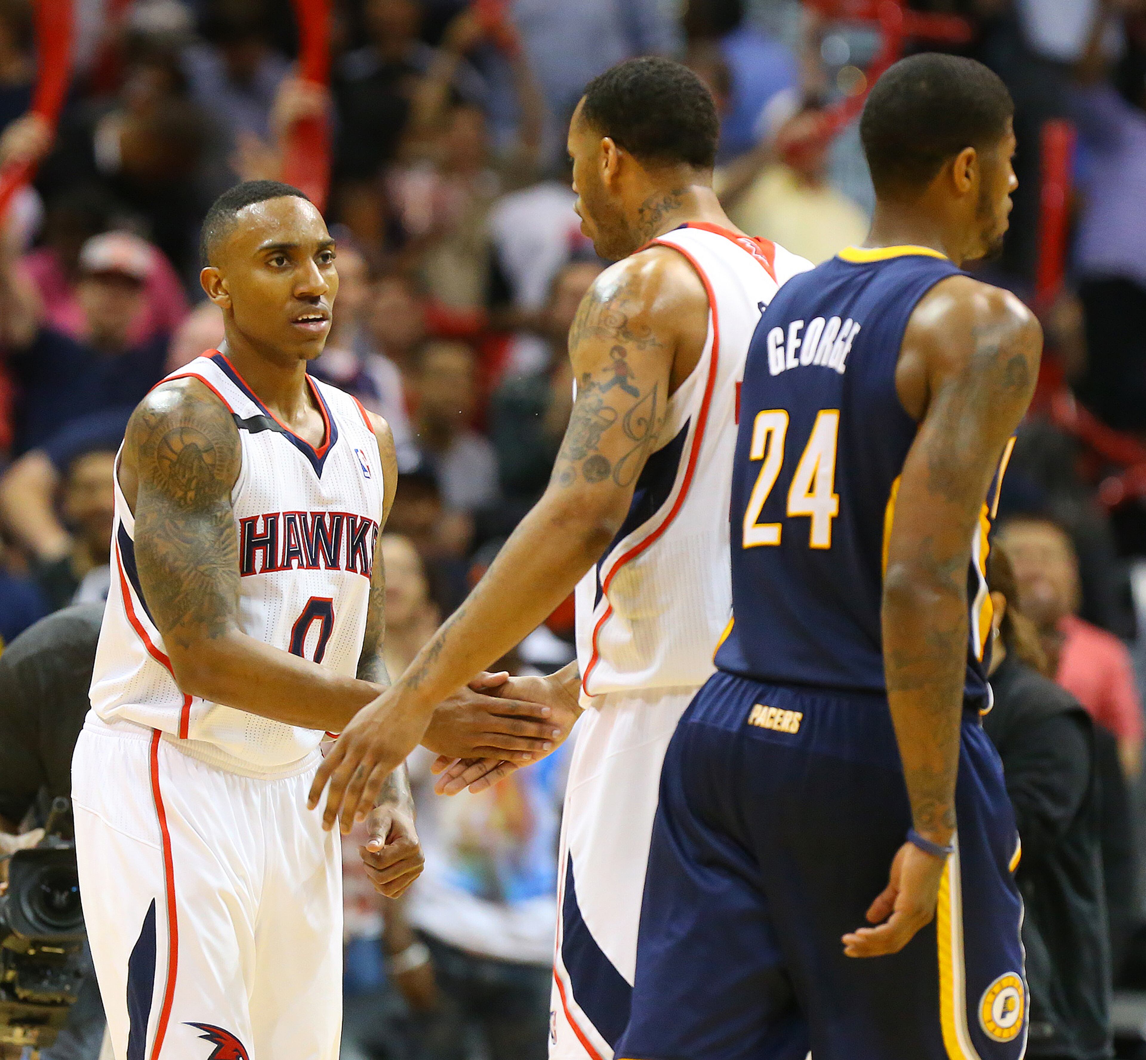 Hawks Jeff Teague and Mike Scott celebrate as Pacers Paul George walks off the court for a time out in the final minutes on the way to beating the Pacers 98-85 for a 2 games to 1 lead during the second half of their NBA playoff game on Thursday, April 24, 2014, in Atlanta. CURTIS COMPTON / CCOMPTON@AJC.COM