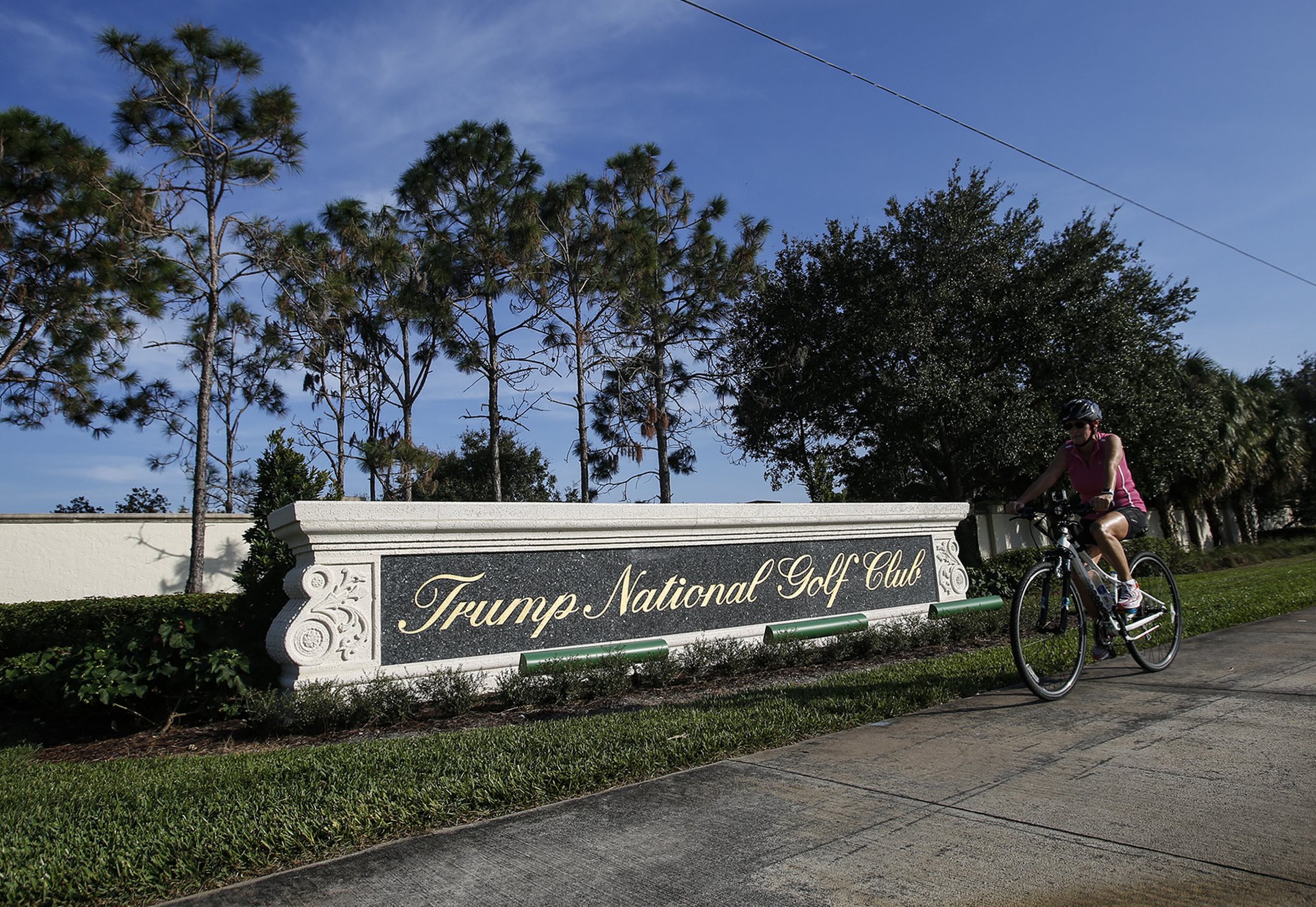 A bike rides by the sign of Trump National Golf Club on Nov. 11, 2016, in Jupiter. (Yuting Jiang / The Palm Beach Post)