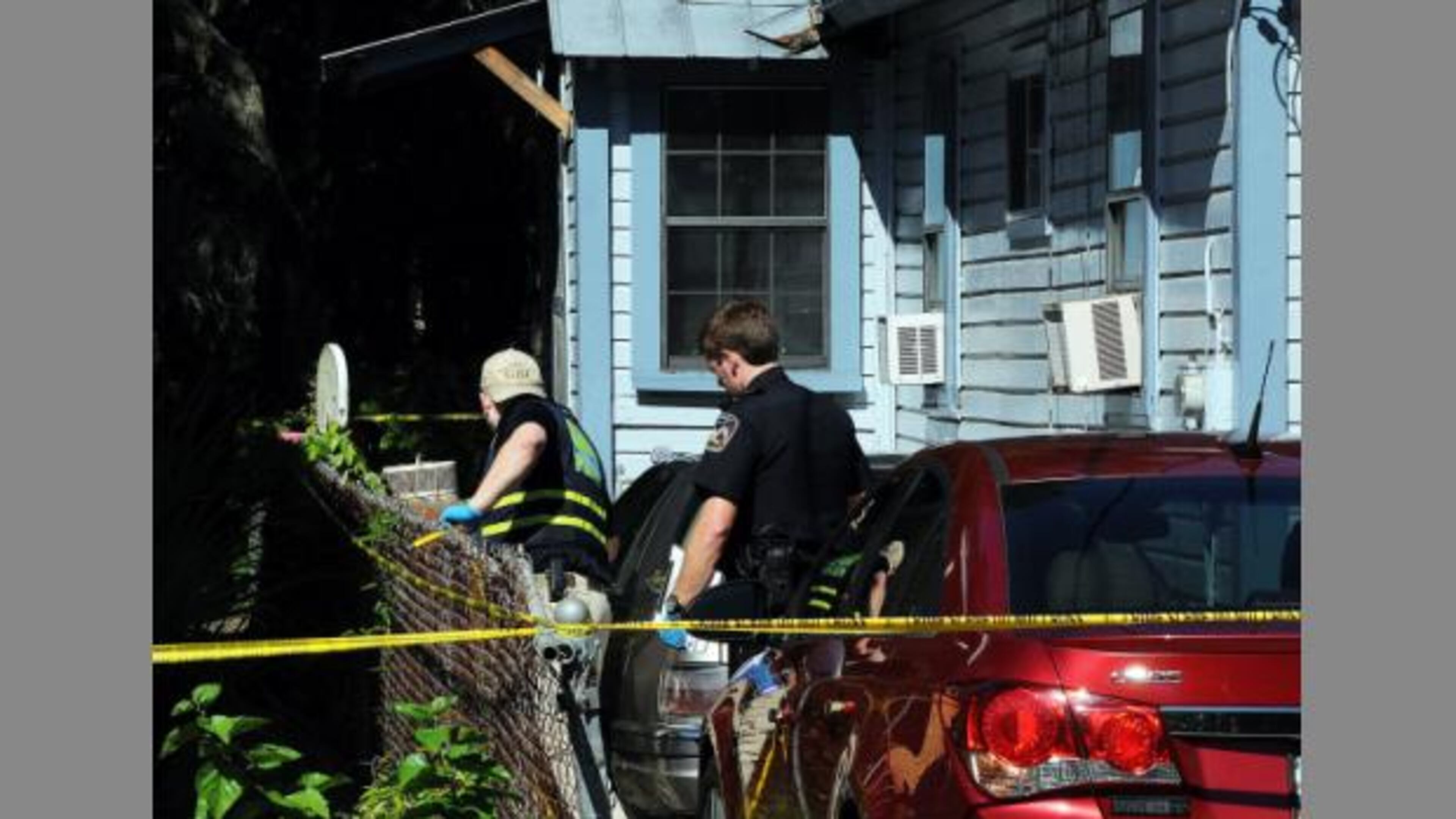 A GBI agent (left) and a Brunswick police officer search a home where a couple and their adult grandson died of gunshot wounds. (Credit: Florida Times-Union)