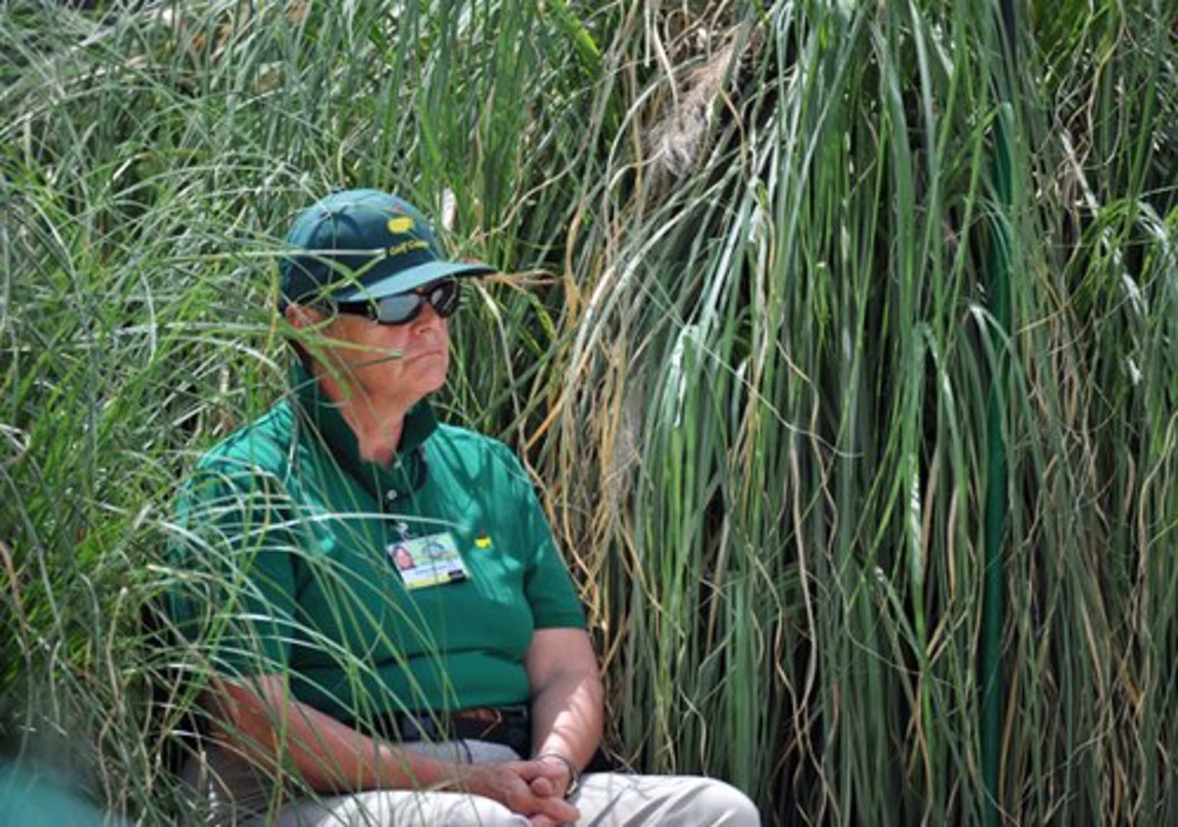Course worker Karne Brown sits in a clump of grass as she monitors the 4th green during the par three contest at the Augusta National Wednesday April 7, 2010.
