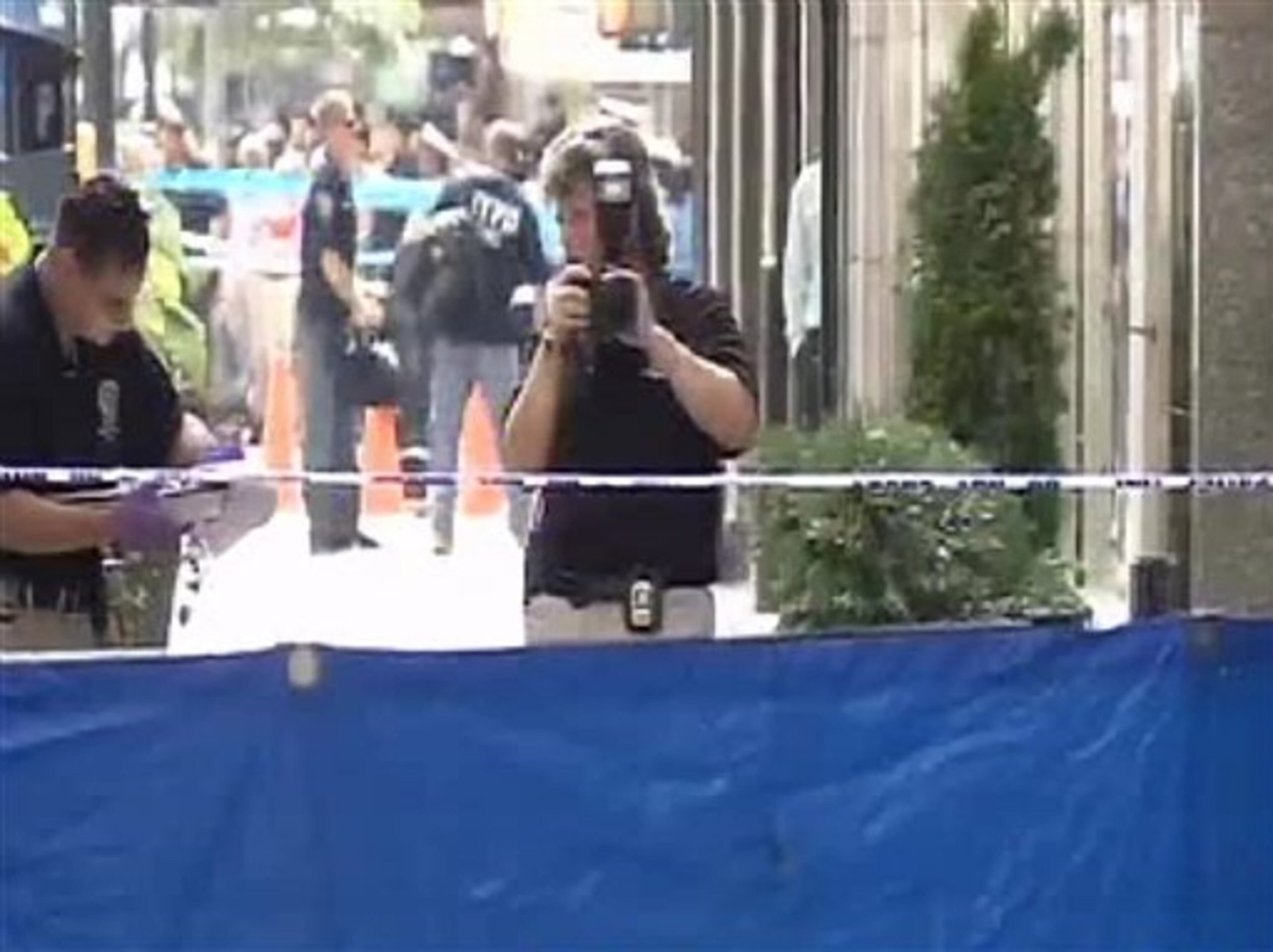 In this frame grab from AP video, authorities photograph the scene where a body lies after a shooting near the Empire State Building, Friday, Aug. 24, 2012, in New York. At least four people were shot outside New York City's Empire State Building on Friday morning and the gunman was dead, New York City officials said. A witness said the gunman was firing indiscriminately. (AP Photo/AP video)