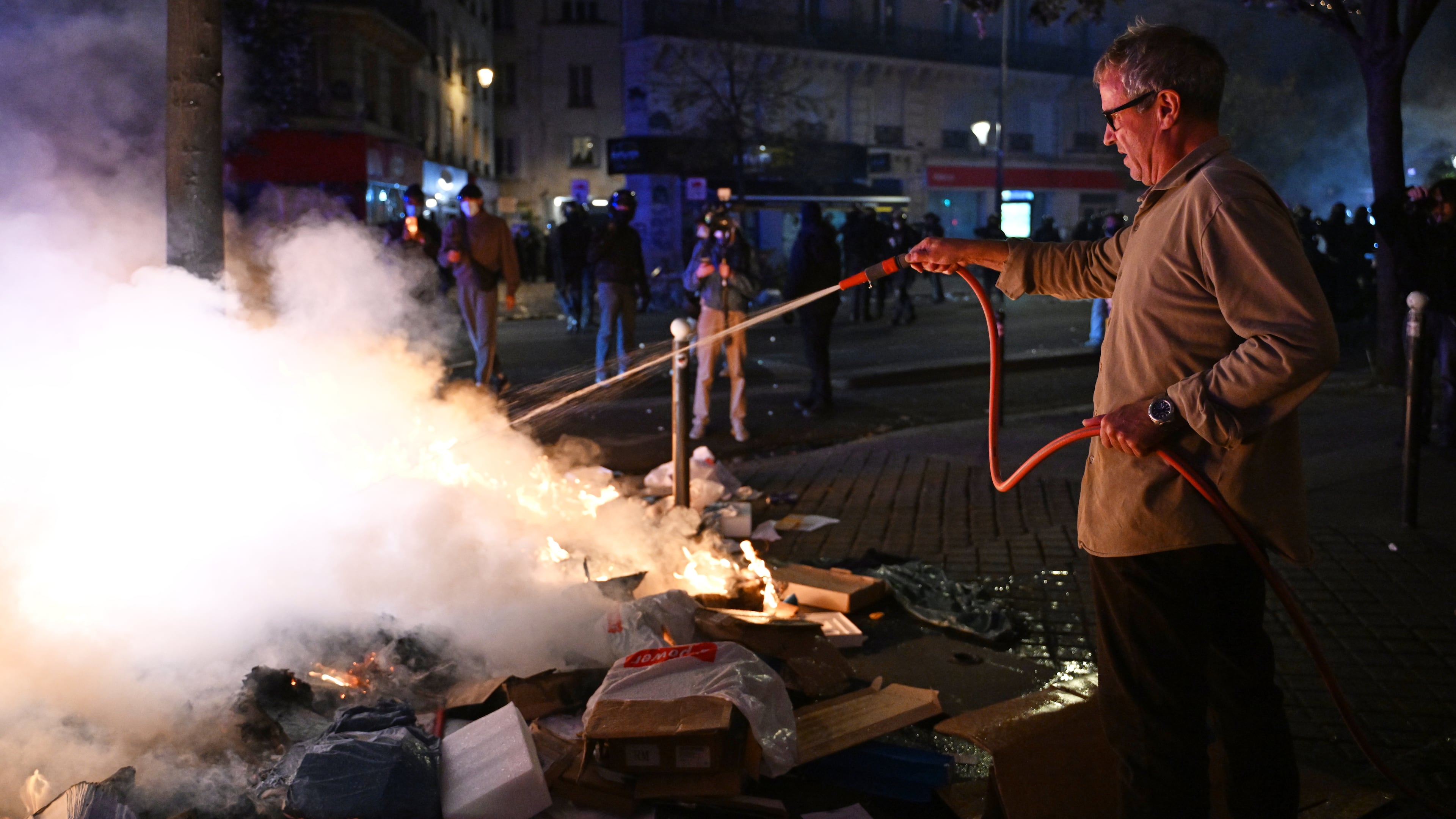 A man tries to extinguish a fire during clashes between protesters and police in Paris, Sunday, Oct. 18, 2026. (AP Photo/Emma Da Silva)