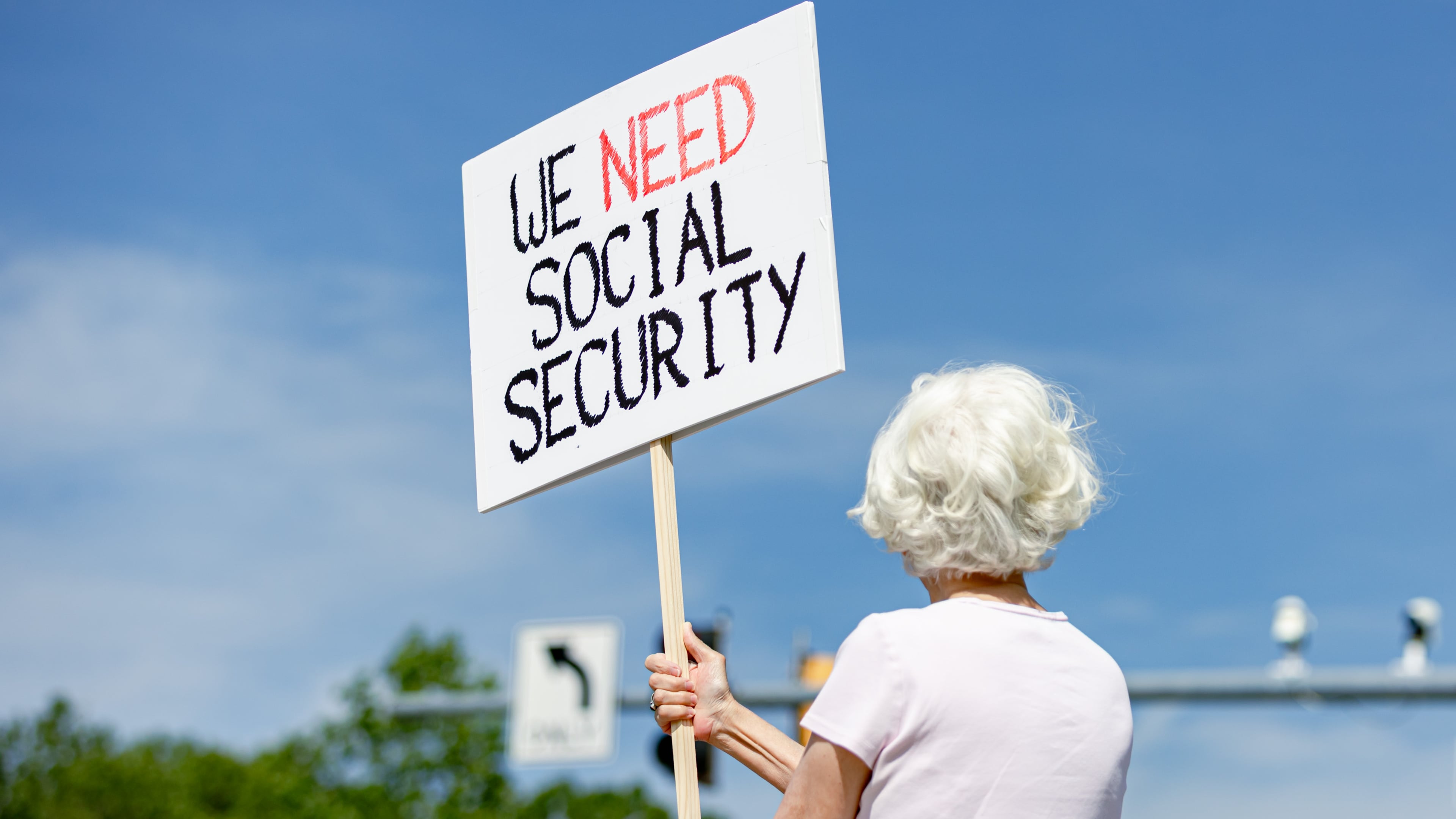 Lynn McKerral holds a sign supporting Social Security Administration workers on Security Boulevard in front of the agency's headquarters in Woodlawn, Md., on Tuesday, May 20, 2025. (Wesley Lapointe for The Washington Post via Getty Images)