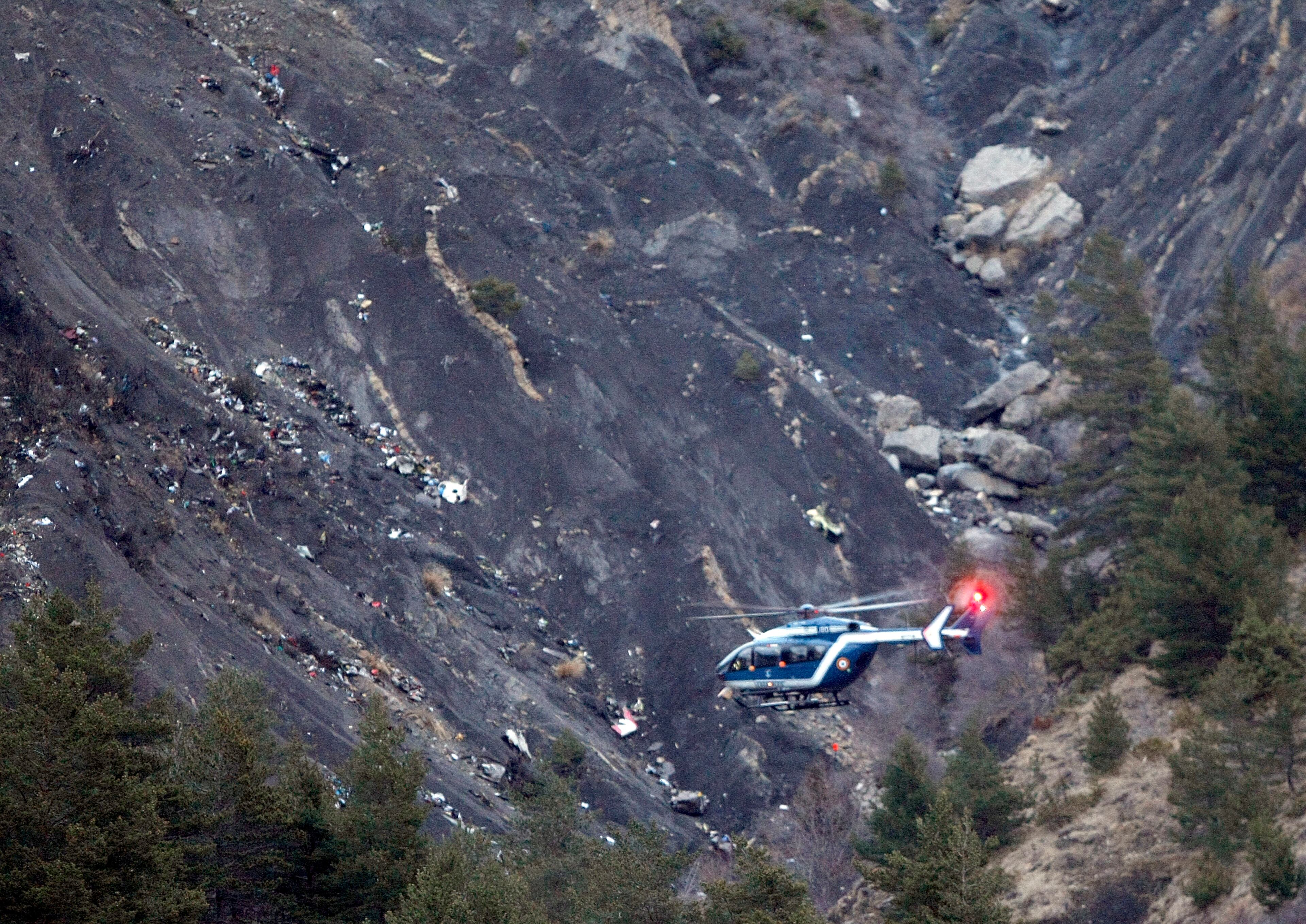 A rescue helicopter flies over debris of the Germanwings passenger jet, scattered on the mountain side, near Seyne les Alpes, French Alps, Tuesday, March 24, 2015. A Germanwings passenger jet carrying at least 150 people crashed Tuesday in a snowy, remote section of the French Alps, sounding like an avalanche as it scattered pulverized debris across the mountain. (AP Photo/Claude Paris)