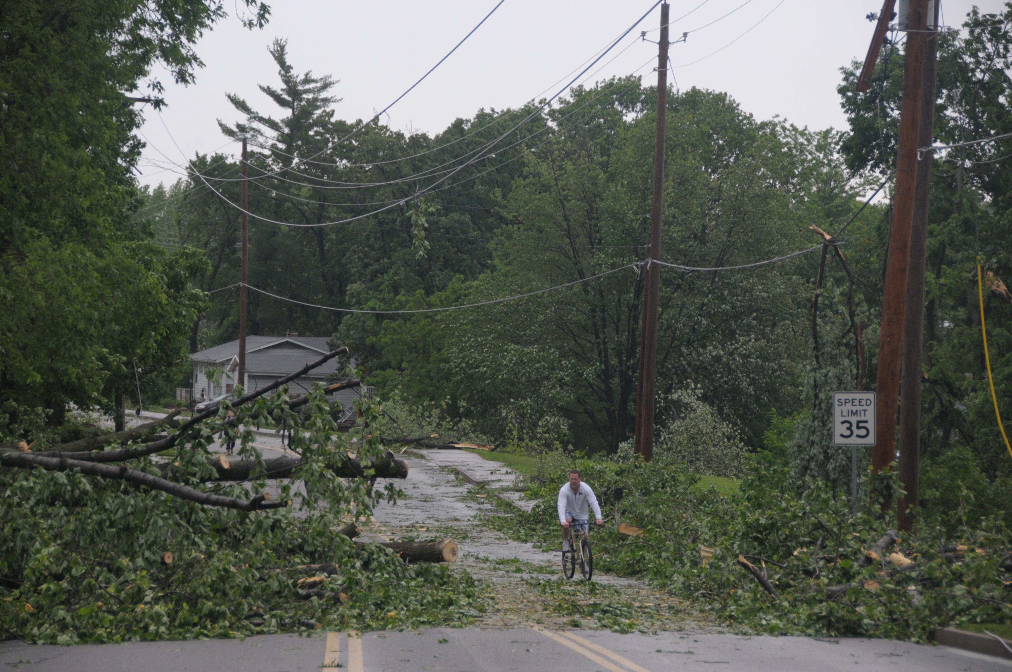 A man rides his bicycle along Caulks Hill Road Saturday, June 1, 2013 after Friday night's storm that hit the Harvester, Mo., area in St. Charles County. Emergency officials set out Saturday morning to see how much damage a violent burst of thunderstorms and tornadoes caused as it swept across the Midwest overnight. (AP Photo/St. Louis Post-Dispatch, Gary Hairlson) EDWARDSVILLE INTELLIGENCER OUT; THE ALTON TELEGRAPH OUT