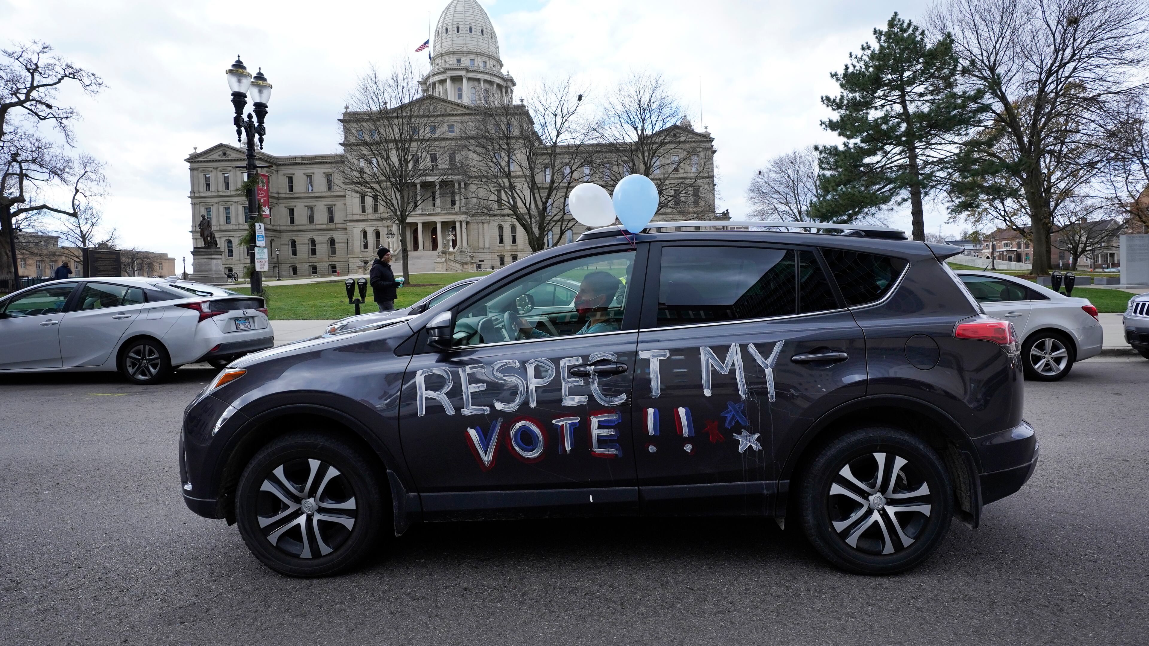 A motorist participates during a drive-by rally to certify the presidential election results near the Capitol building in Lansing, Michigan.