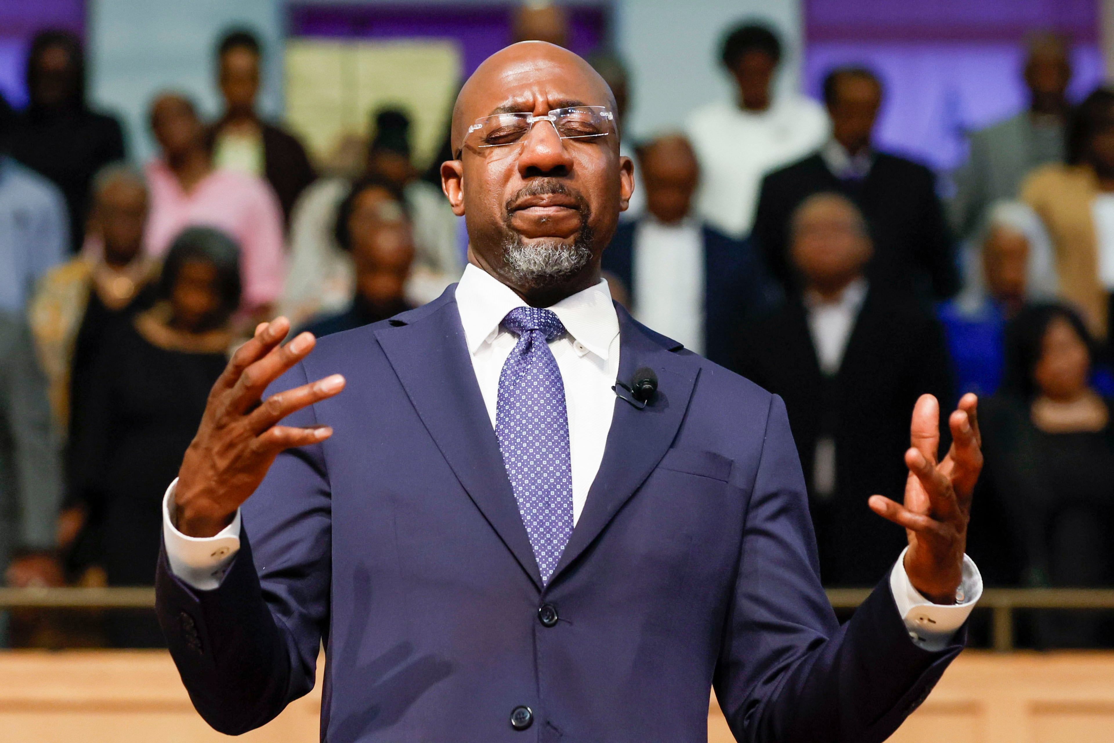U.S. Sen. Raphael Warnock, D-Ga., participates in a prayer at Zion Hill Baptist Church last month. (Miguel Martinez/ AJC)