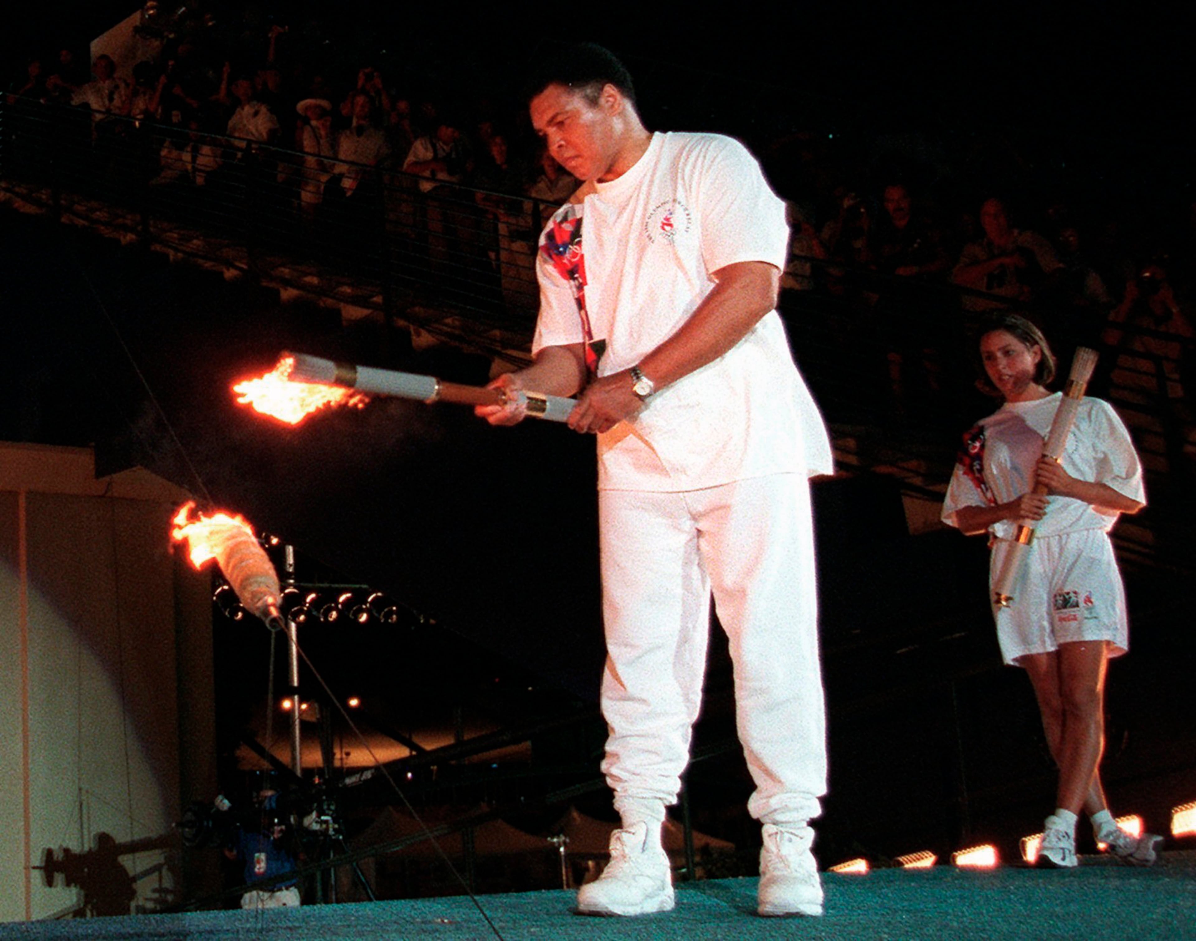 Muhammad Ali lights the Olympic flame during the 1996 Summer Olympic Games opening ceremony in Atlanta as American swimmer Janet Evans looks on, July 19, 1996. (Michael Probst/AP)
