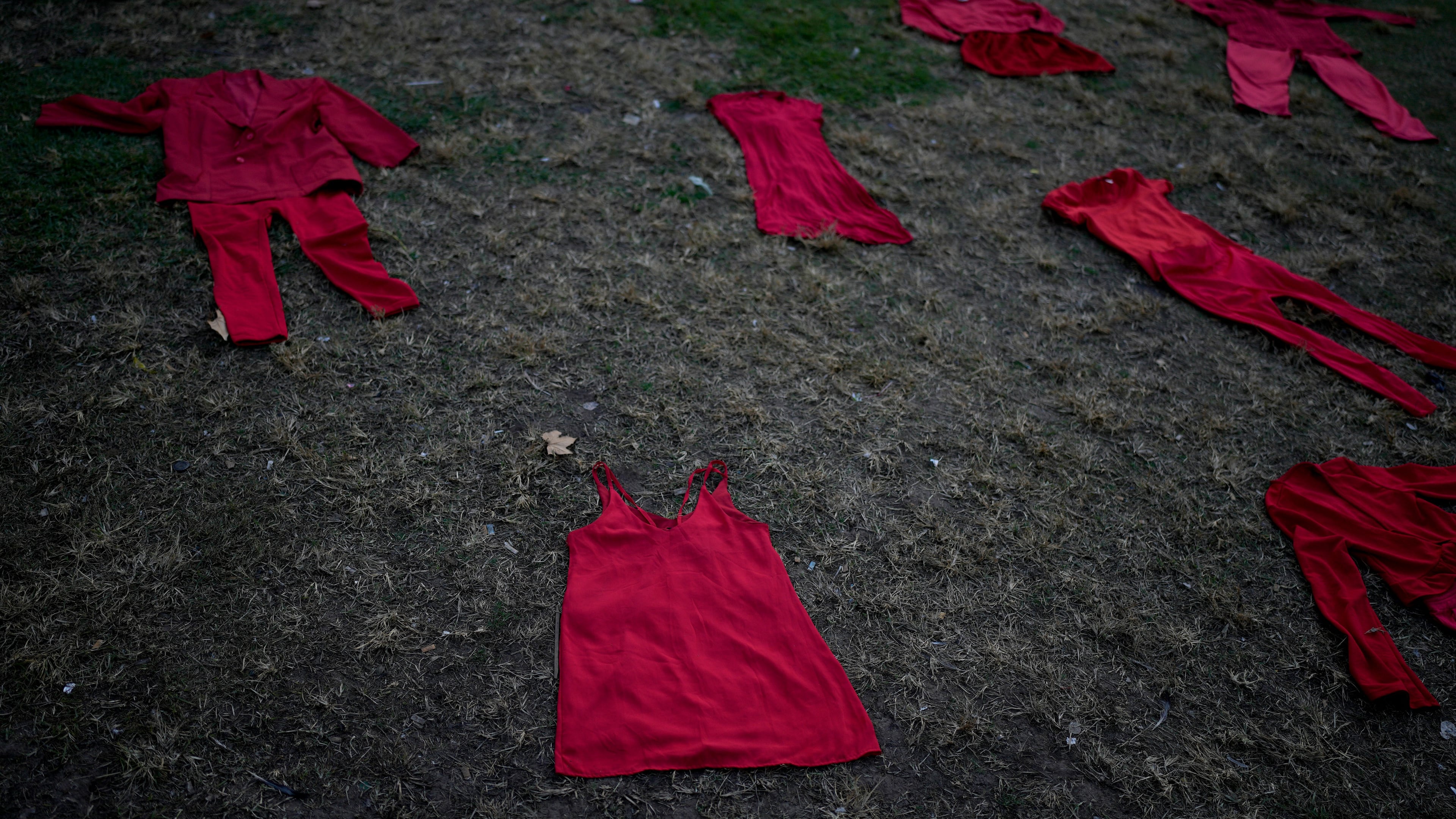 FILE - Outfits representing women who were disappeared or murdered lie on the grass outside Congress during a march marking the ninth anniversary of the "Ni Una Menos" (Not One Fewer) women's movement in Buenos Aires, Argentina, June 3, 2024. (AP Photo/Natacha Pisarenko, File)