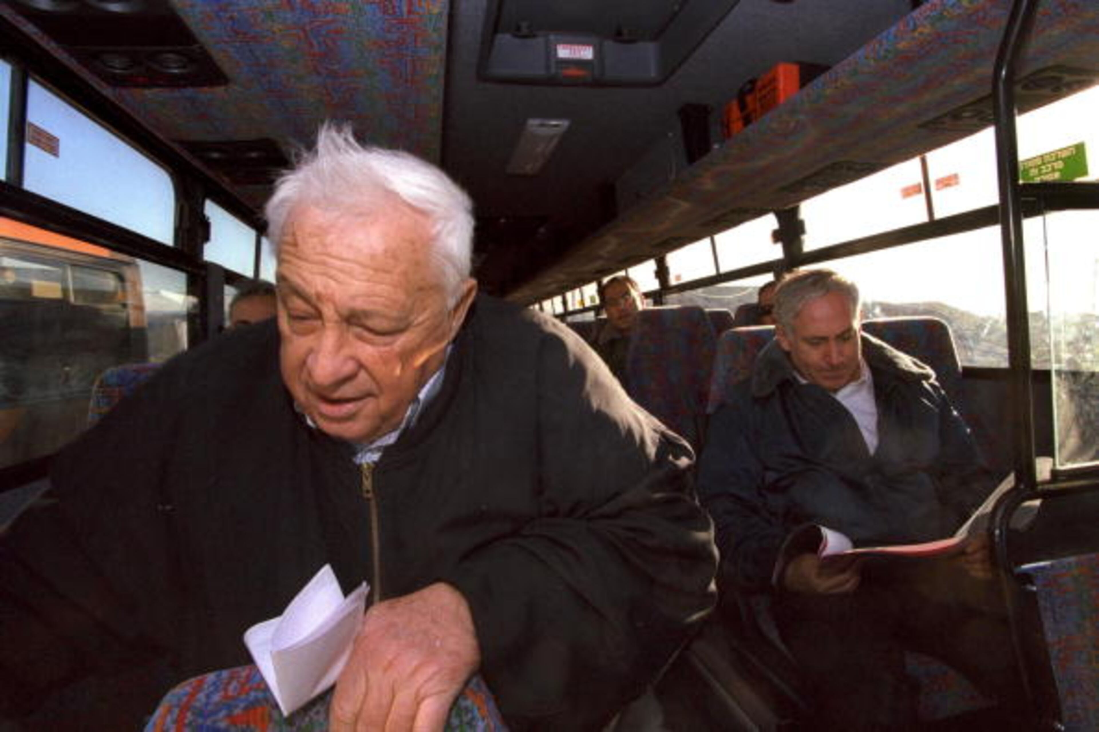 WEST BANK - DECEMBER 28, 1997: Israeli Infrastructure Minister Ariel Sharon (L) and Prime Minister Benjamin Netanyahu (R) ride a bus during a cabinet tour December 28, 1997 of Israeli settlements in the West Bank. Sharon, considered the "Father of the Settlements" who in the 1980's and 1990's helped establish many of the hundreds of Jewish enclaves in the West Bank and Gaza, is now the target of right-wing frustration as his Gaza Strip and northern West Bank disengagement plan approaches its August 15, 2005 starting date. (Photo by Avi Ohayon/GPO via Getty Images)