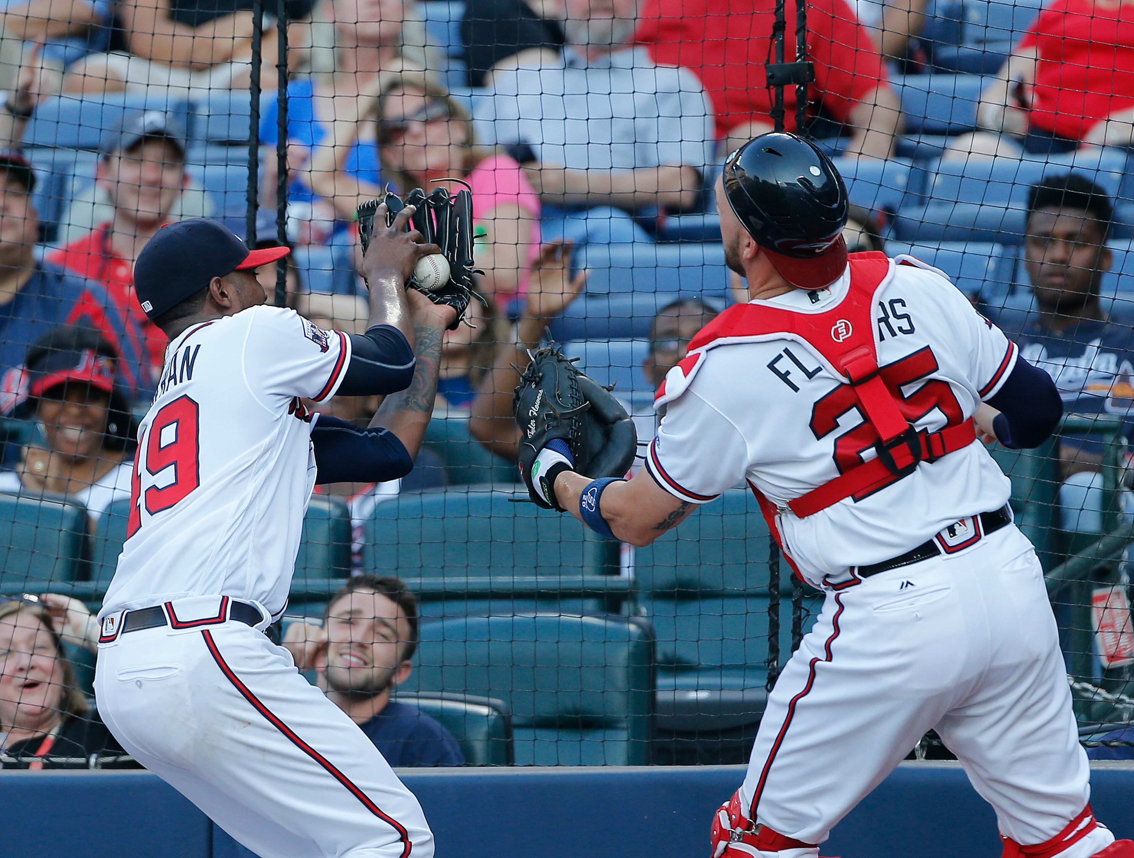 Atlanta Braves starting pitcher Julio Teheran (49) catches a Miami Marlins' Giancarlo Stanton foul ball as catcher Tyler Flowers (25) backs him up in the first inning of a baseball game Friday, July 1, 2016, in Atlanta. (AP Photo/John Bazemore)
