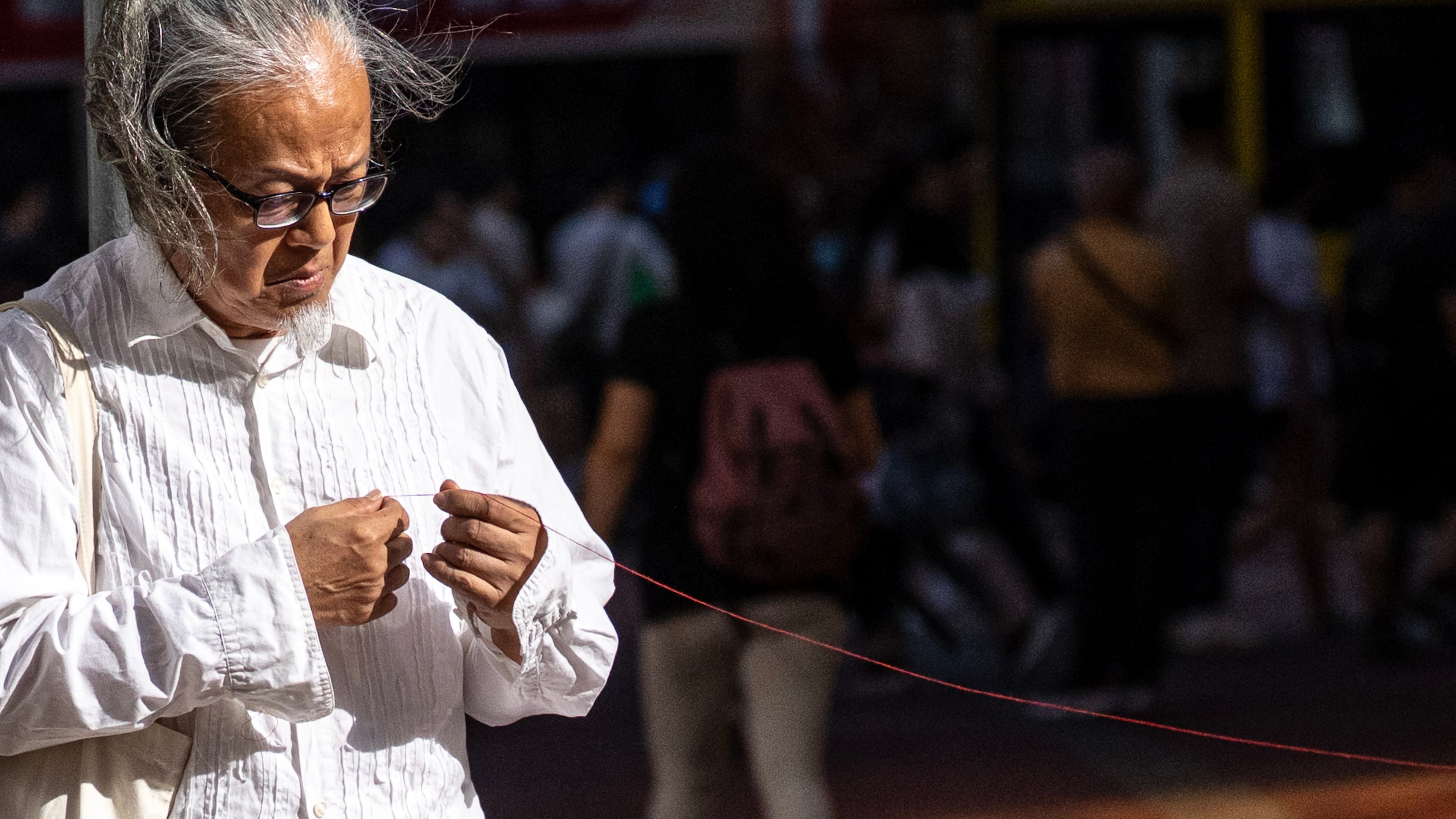 Artist Sanmu Chen displays a red thread as he performs on the street in the Causeway Bay area on the eve of the 37th anniversary of China's Tiananmen Square crackdown in Hong Kong, Wednesday, June 3, 2026. (AP Photo/Chan Long Hei)