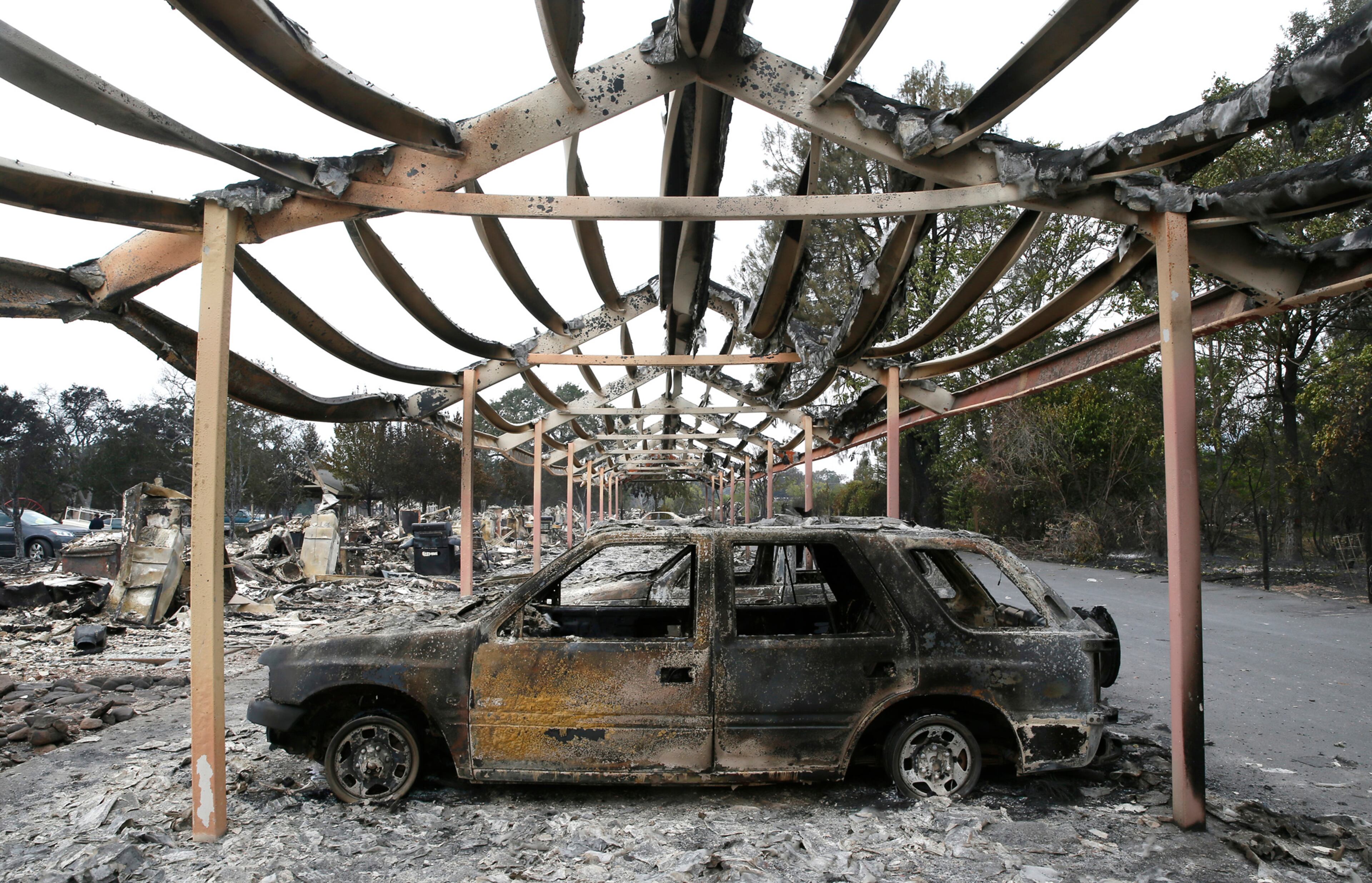The charred metal skeleton of a carport and vehicles left by fleeing residents are all that remain of a two-story apartment complex in Middletown, Calif., on Monday, Sept. 14, 2015, after hundreds fled when the Valley Fire burned much of the town. (Don Bartletti/Los Angeles Times/TNS)