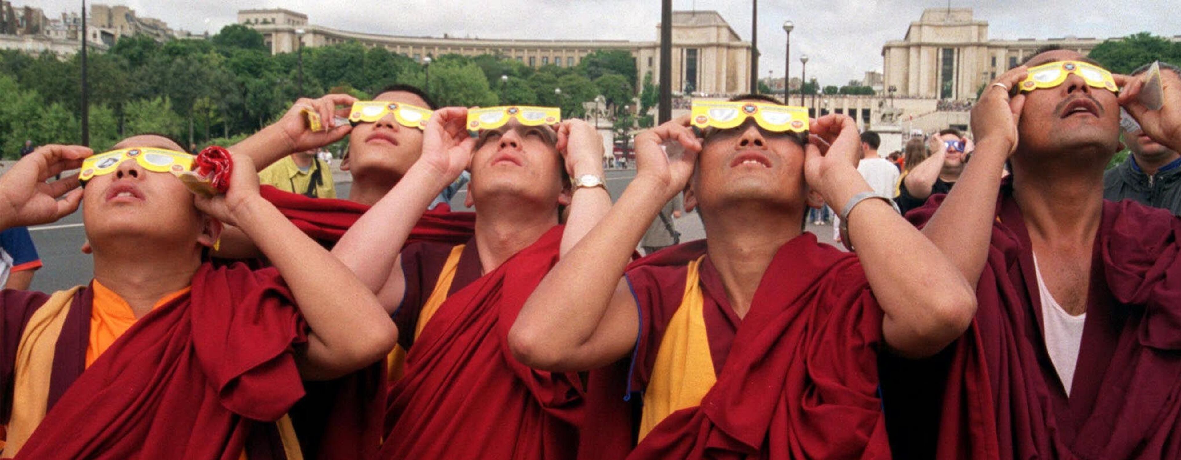 Buddhist monks watch the solar eclipse near the Eiffel Tower in Paris Wednesday, Aug. 11, 1999. The moon smothered the light of the sun Wednesday as the last total solar eclipse of the millennium swept across Europe toward the Bay of Bengal. (AP Photo/Jacques Brinon)