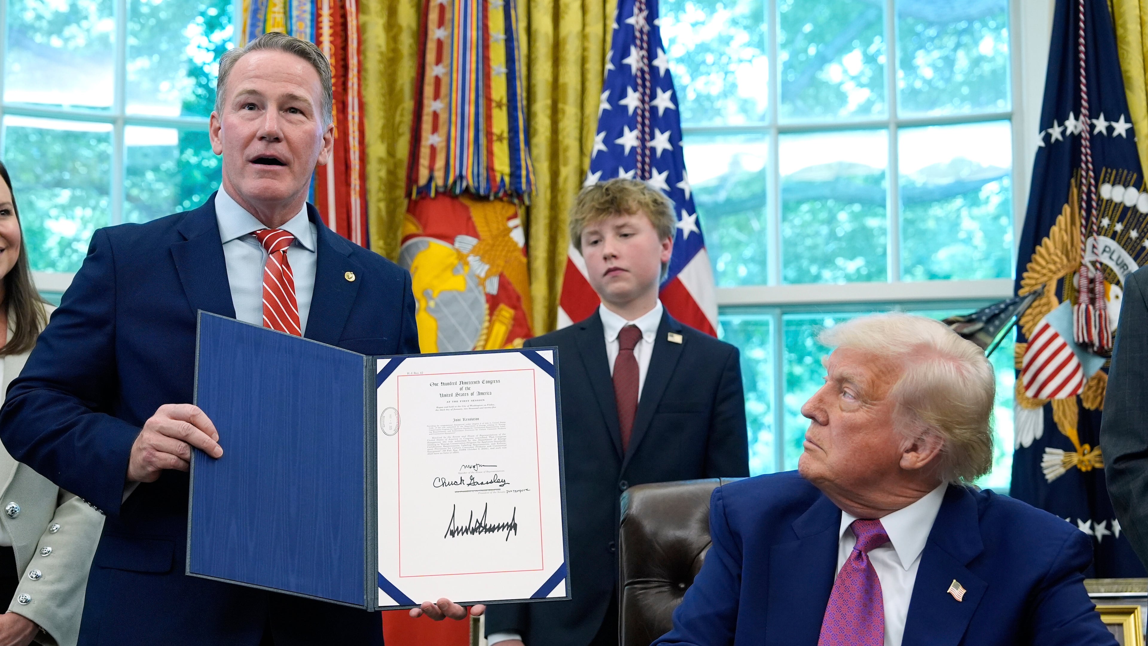 FILE - President Donald Trump listens as Sen. Jon Husted, R-Ohio, speaks while holding up a signed resolution in the Oval Office of the White House, May 9, 2025, in Washington. (AP Photo/Alex Brandon, File)