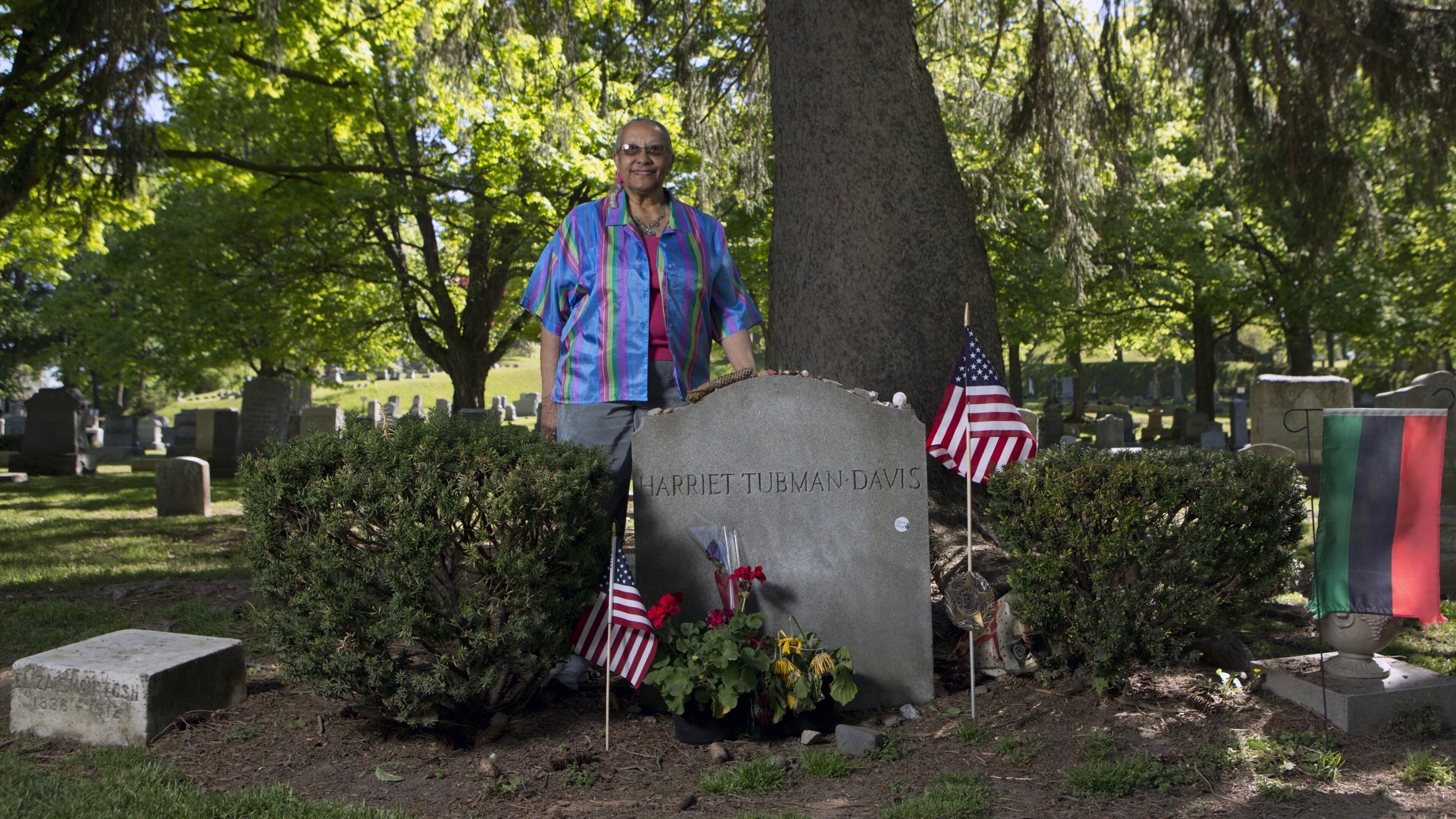 In this Thursday, May 19, 2016 photo, Judith Bryant, a great-great-grandniece of Harriet Tubman, poses at Tubman’s grave site at Fort Hill Cemetery in Auburn, N.Y. Tubman’s upcoming debut on the $20 bill is just half the good news in the upstate New York town where the Underground Railroad conductor settled down and grew old. Bryant’s great-great grandfather was Tubman’s brother, and was among the dozens of slaves she guided north to freedom. (AP Photo/Mike Groll)