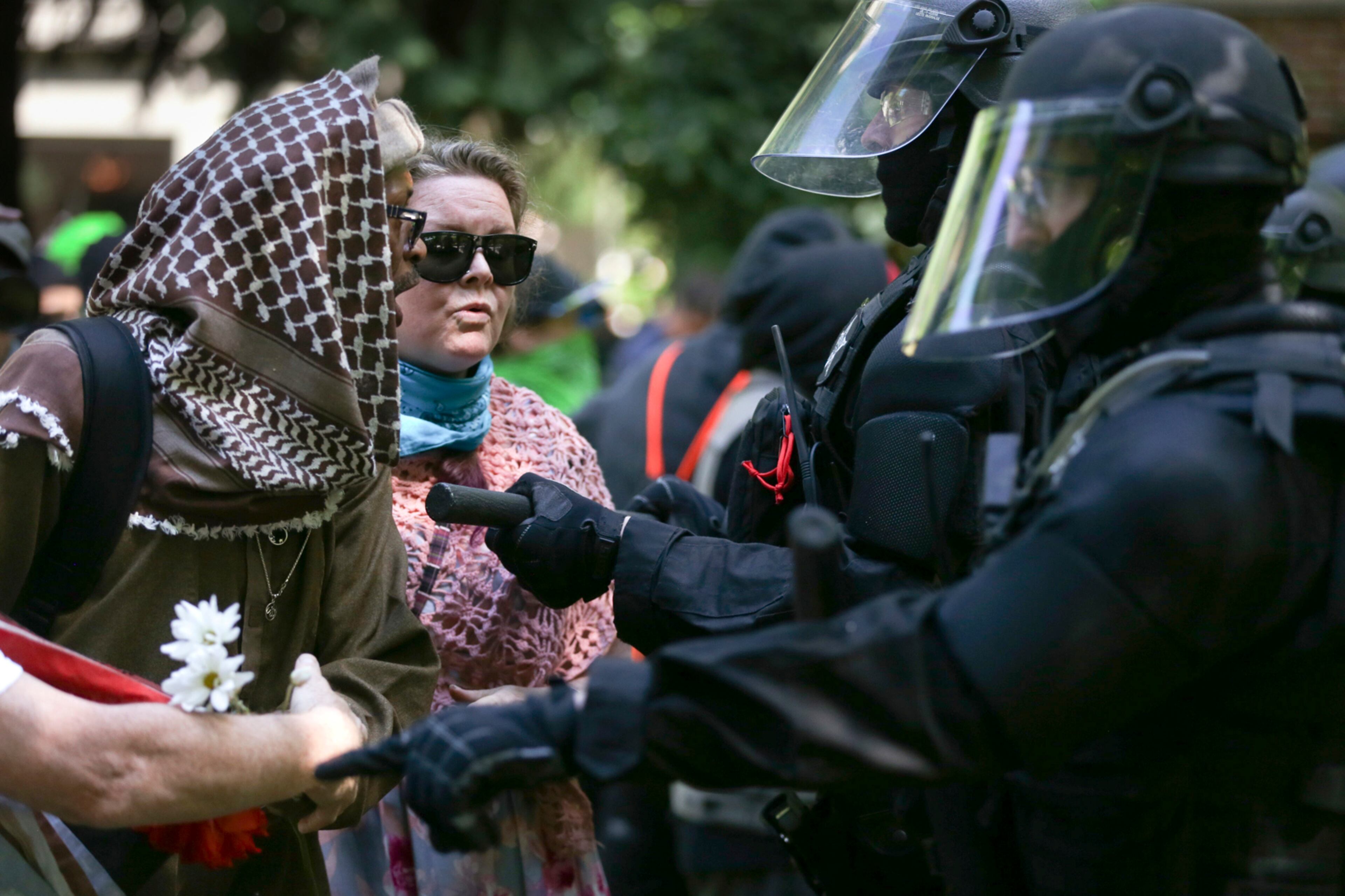 Police officers move to clear demonstrators from Chapman Square near City Hall in downtown Portland, Oreg., Sunday, June 4, 2017, declaring it an unlawful assembly, as they gathered following last month's fatal stabbing of two men who tried to stop another man's anti-Muslim tirade. A pro-Donald Trump free speech rally organized by a conservative group drew hundreds near City Hall. The group was met by hundreds of counter-protesters organized by immigrant rights, religious and labor groups. (Dave Killen/The Oregonian via AP)