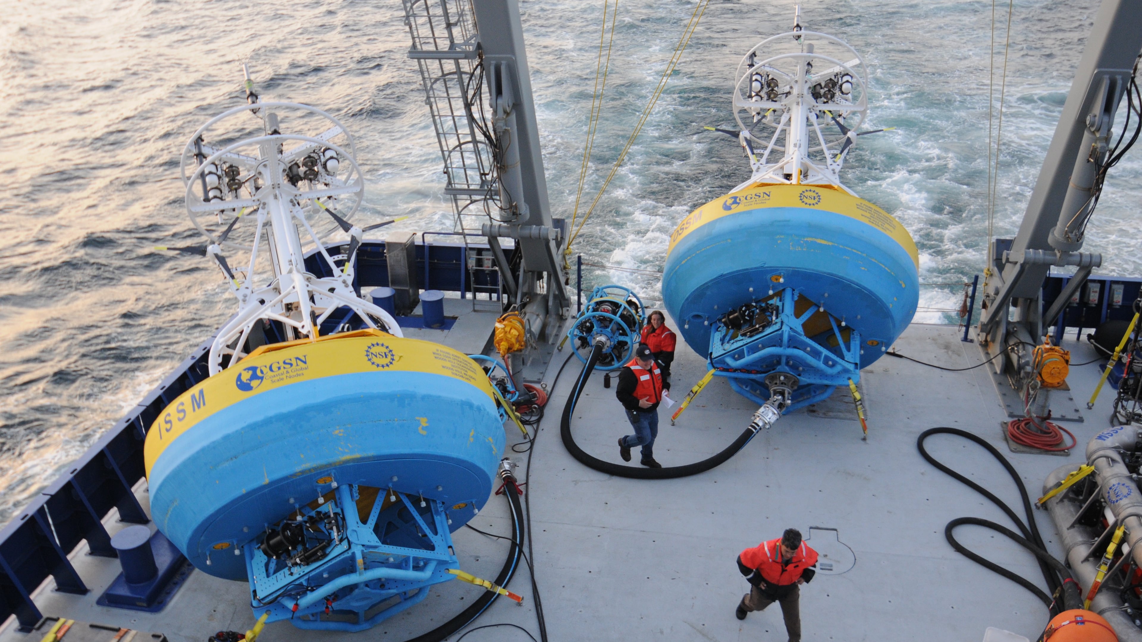 In this 2021 image provided by Woods Hole Oceanographic Institution, workers walk near buoys used to gather data at Pioneer New England shelf off the coast of Martha’s Vineyard, Mass. (Véronique LaCapra/Woods Hole Oceanographic Institution via AP)