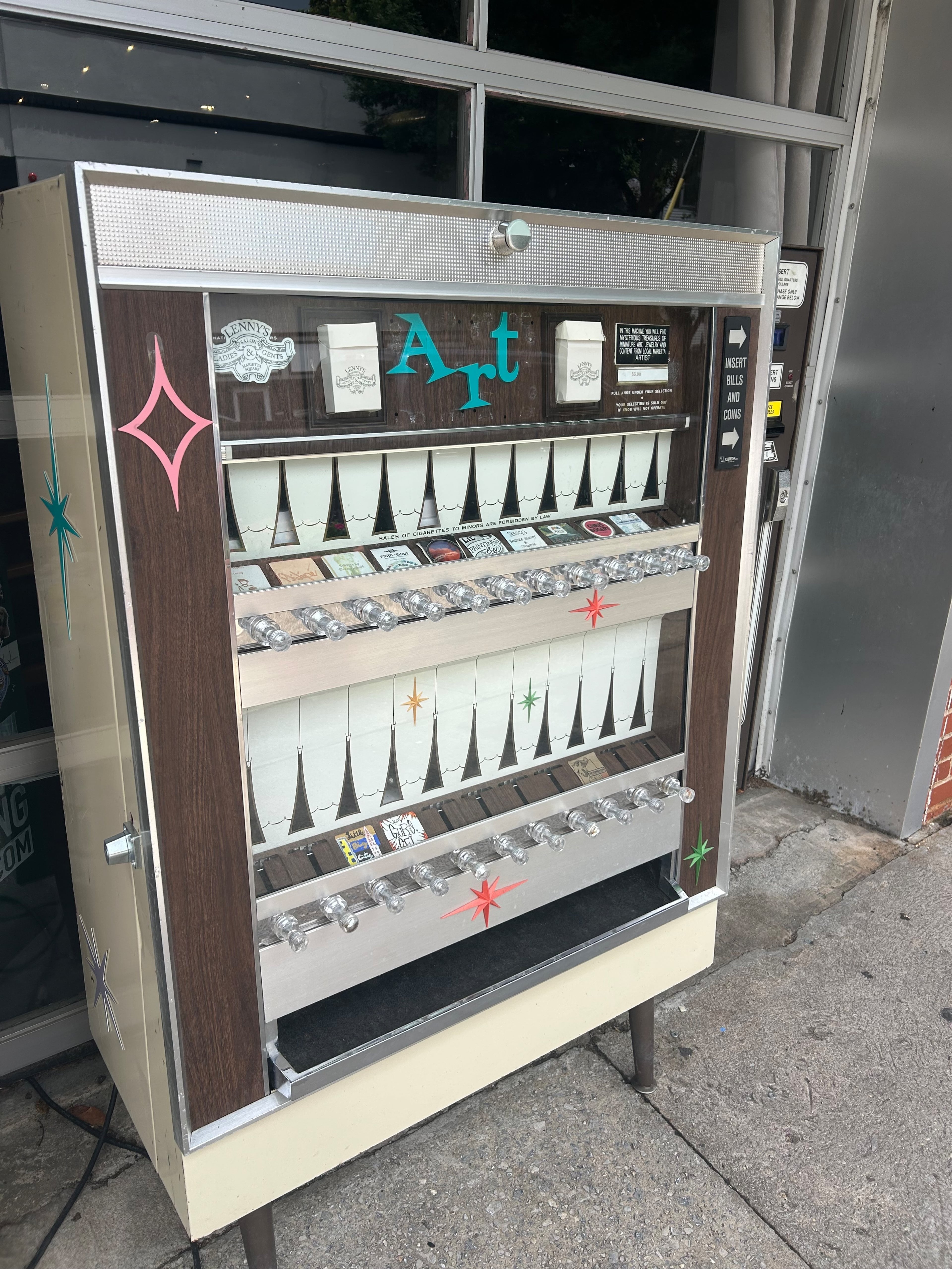 Lenny's Hair Salon in Marietta Square has an art vending machine sitting outside his salon with local art. (Olivia Wakim / AJC)