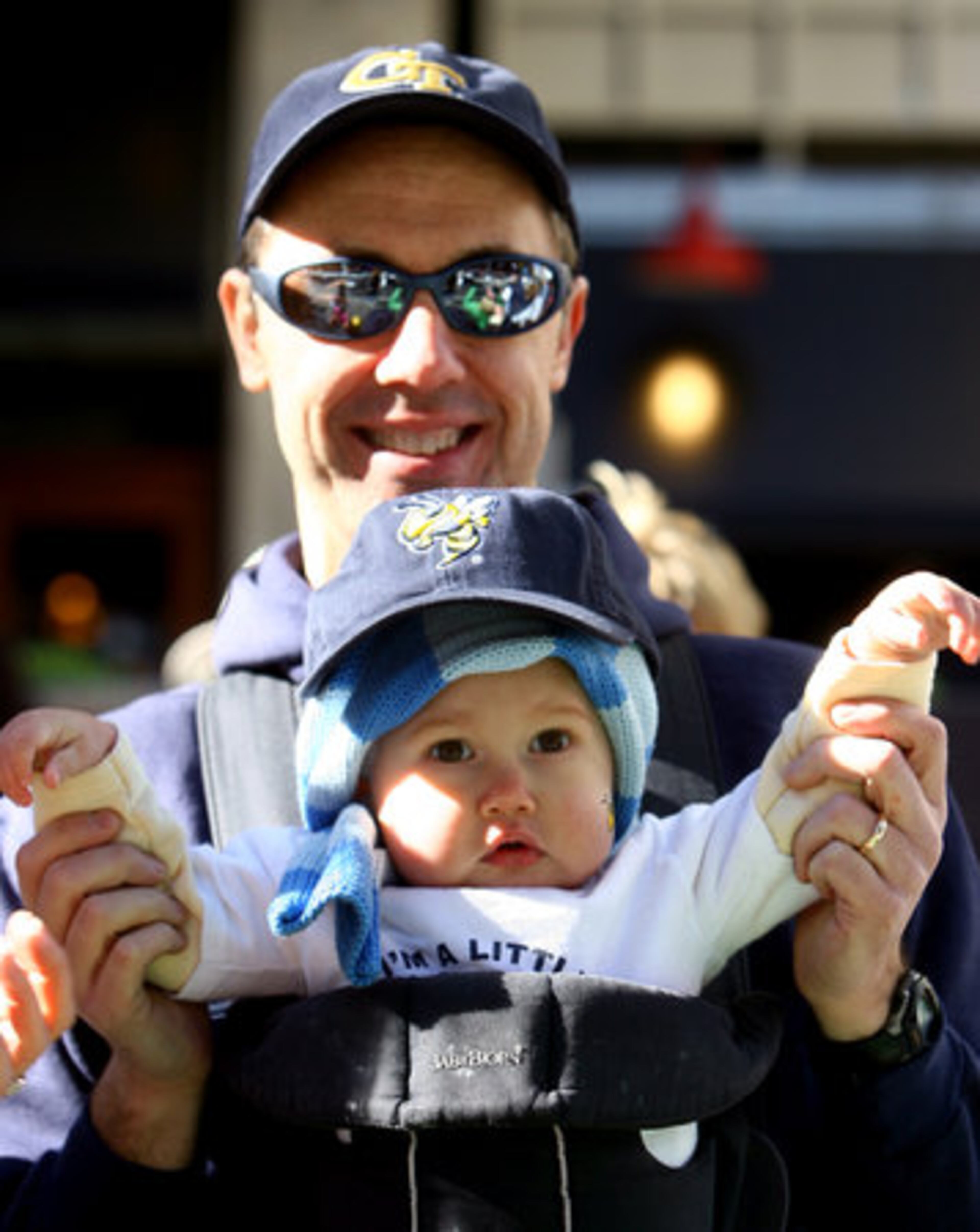 Joe Knoerle of Atlanta, a 1990 Georgia Tech grad, watches the parade with daughter Mary Ellen Knoerle, age 15 months, along Peachtree Street.