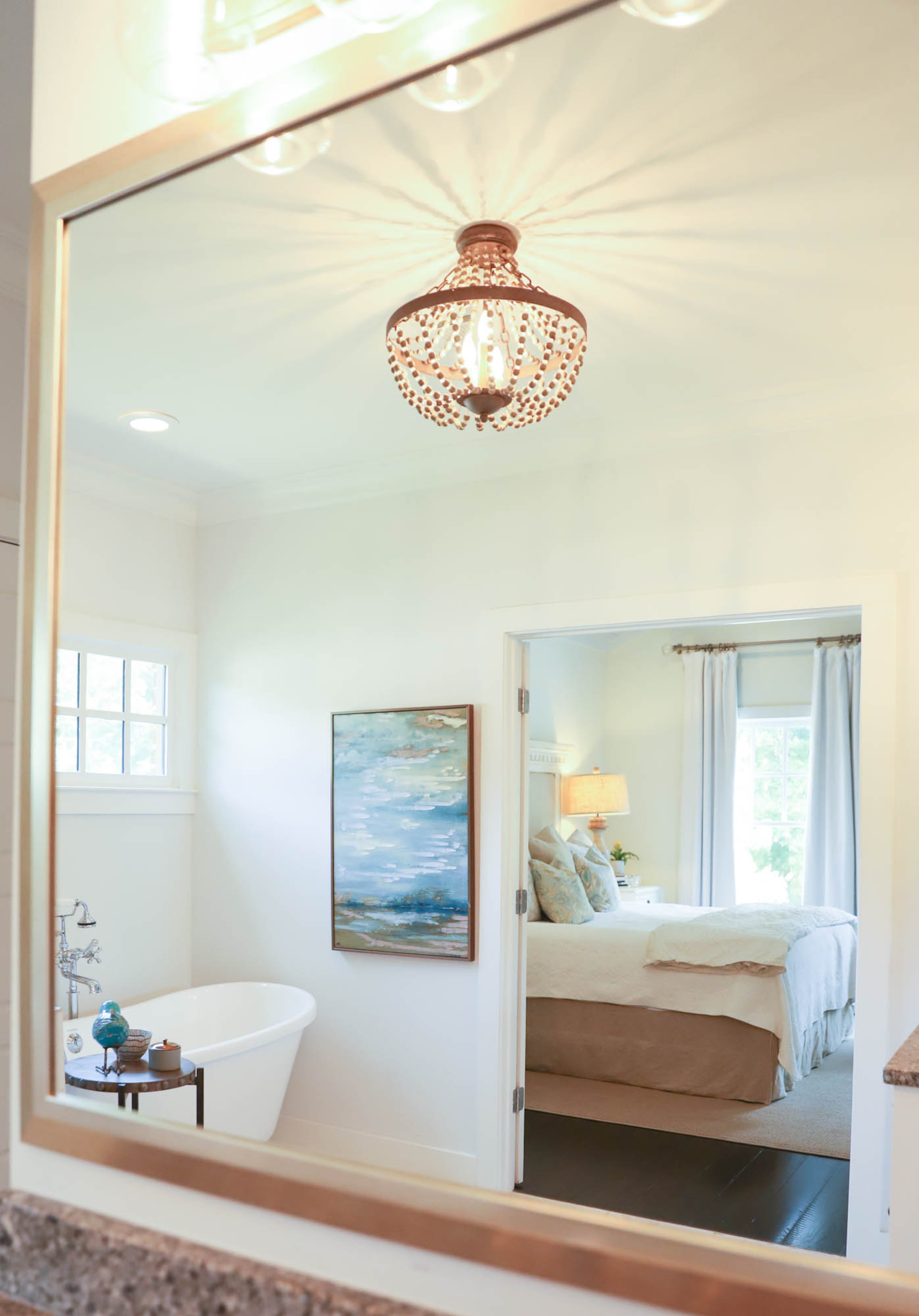 The light fixture from Progressive Lighting adds elegant flair to Paige Henkel's and Steve Schwartz's master bath. The painting on the wall draws in the ocean theme, which can be found throughout their home in art, books and seashells.