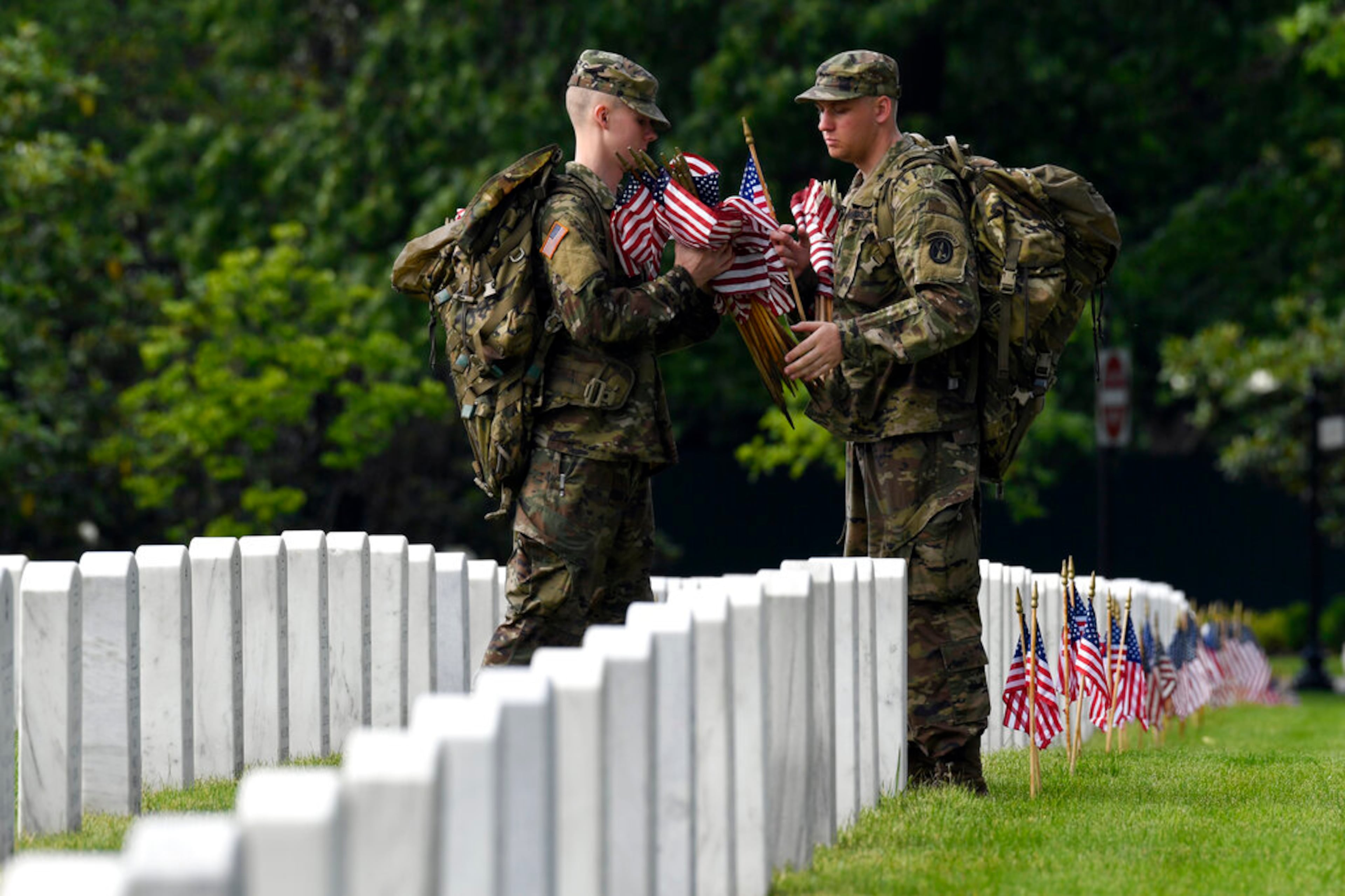 Members of the 3d U.S. Infantry Regiment, also known as The Old Guard, place flags in front of each headstone for "Flags-In" at Arlington National Cemetery in Arlington, Va., Thursday, May 23, 2019, to honor the Nation's fallen military heroes. (AP Photo/Susan Walsh)