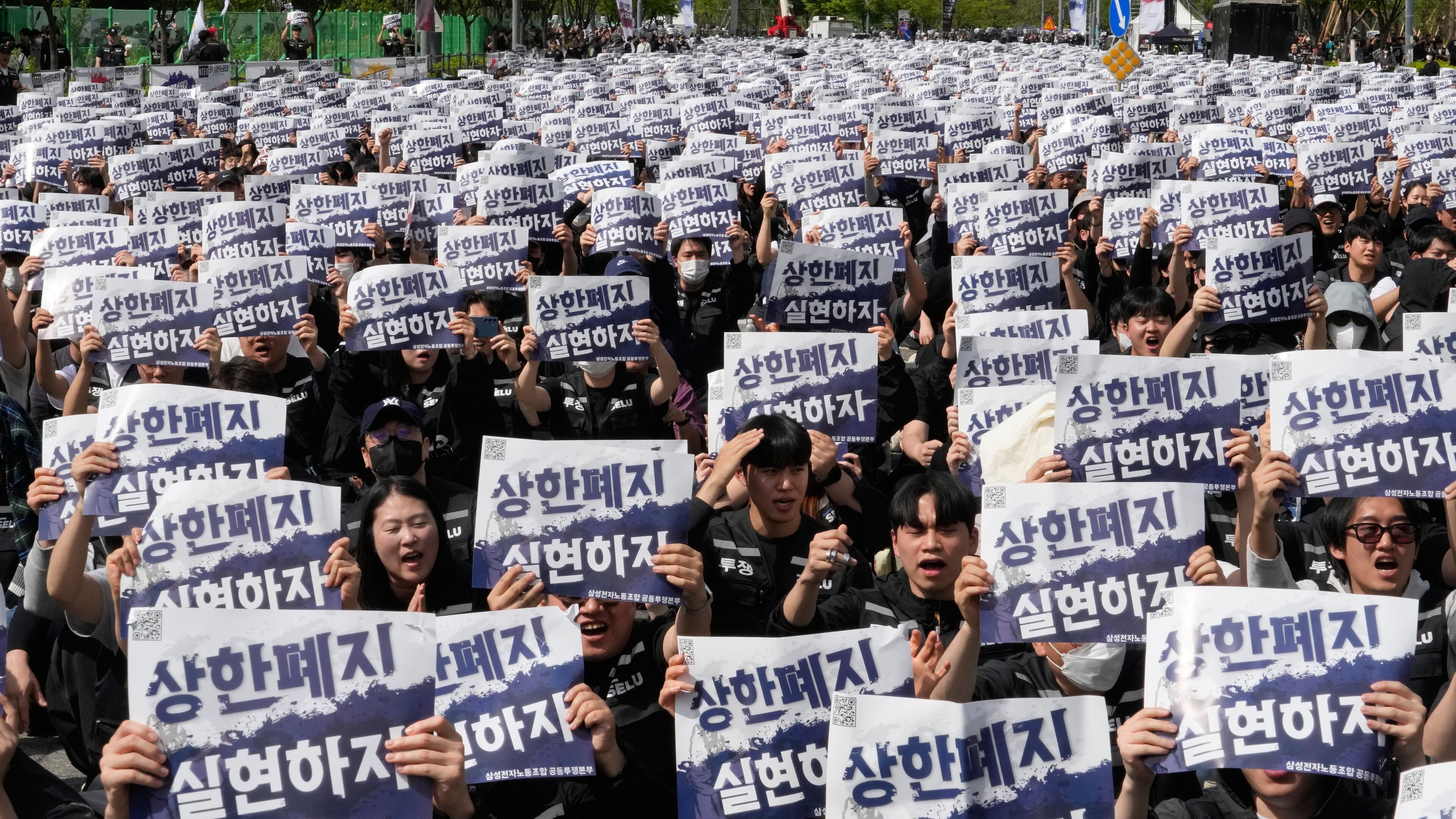 Members of the Samsung Electronics labor union hold up their cards during a rally demanding higher bonuses at its computer chip complex in Pyeongtaek, South Korea, Thursday, April 23, 2026. The letters read "Remove the bonuses caps." (AP Photo/Ahn Young-joon)