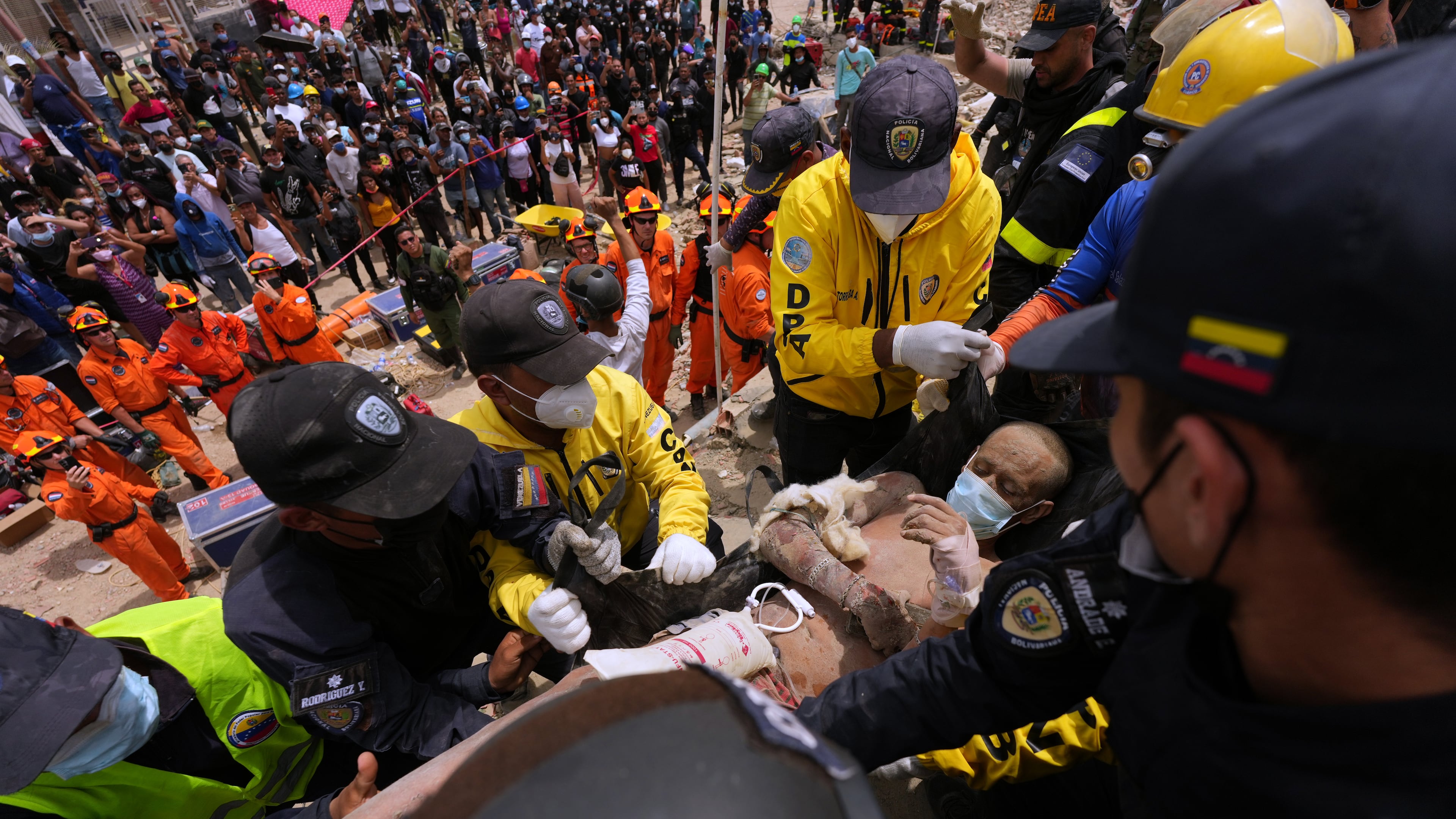 Rescue workers carry a mans rescued from the rubble of a building that collapsed in the earthquakes that struck La Guaira, Venezuela, Sunday, June 28, 2026. (AP Photo/Matias Delacroix)