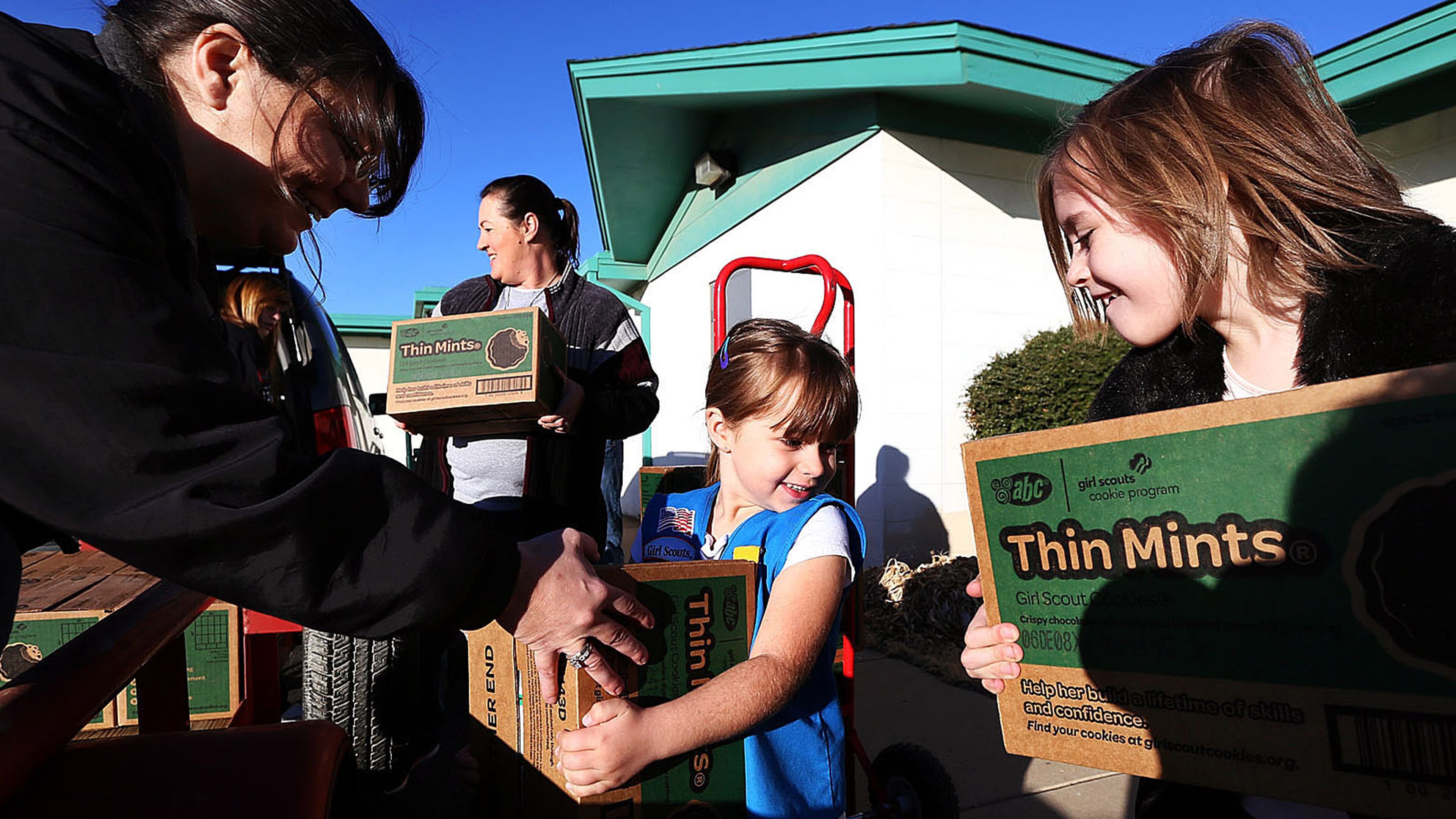 Daisy Samantha Weathers, center, and Brownie Madeline Taylor help bring out cases of cookies to Tatum Roe, volunteer product sales committee member with the Girl Scouts of the Desert Southwest, as she stacks them on a trailer bed for the 41018 troop which has 381 cases of cookies for the start of the Girl Scout Cookie Sale Program.