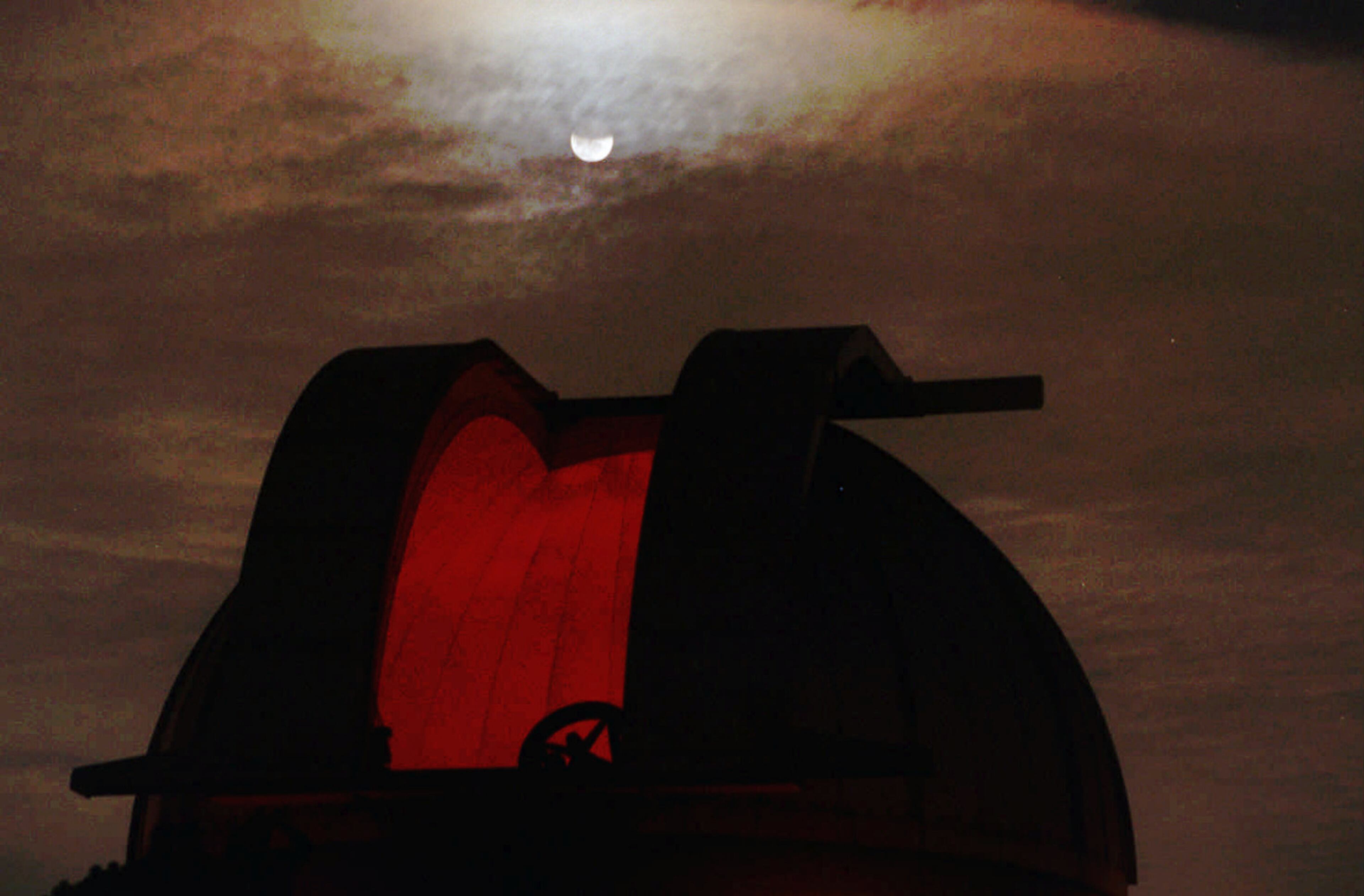 The moon starts to come out of its umbra after an eclipse Wednesday night, April 3, 1996, as it rises over the observatory at Fernbank Science Museum. The possibility of being able to see comet Hyakutake also brought out a crowd of about 300 people. (AJC photo/Frank Niemeir)