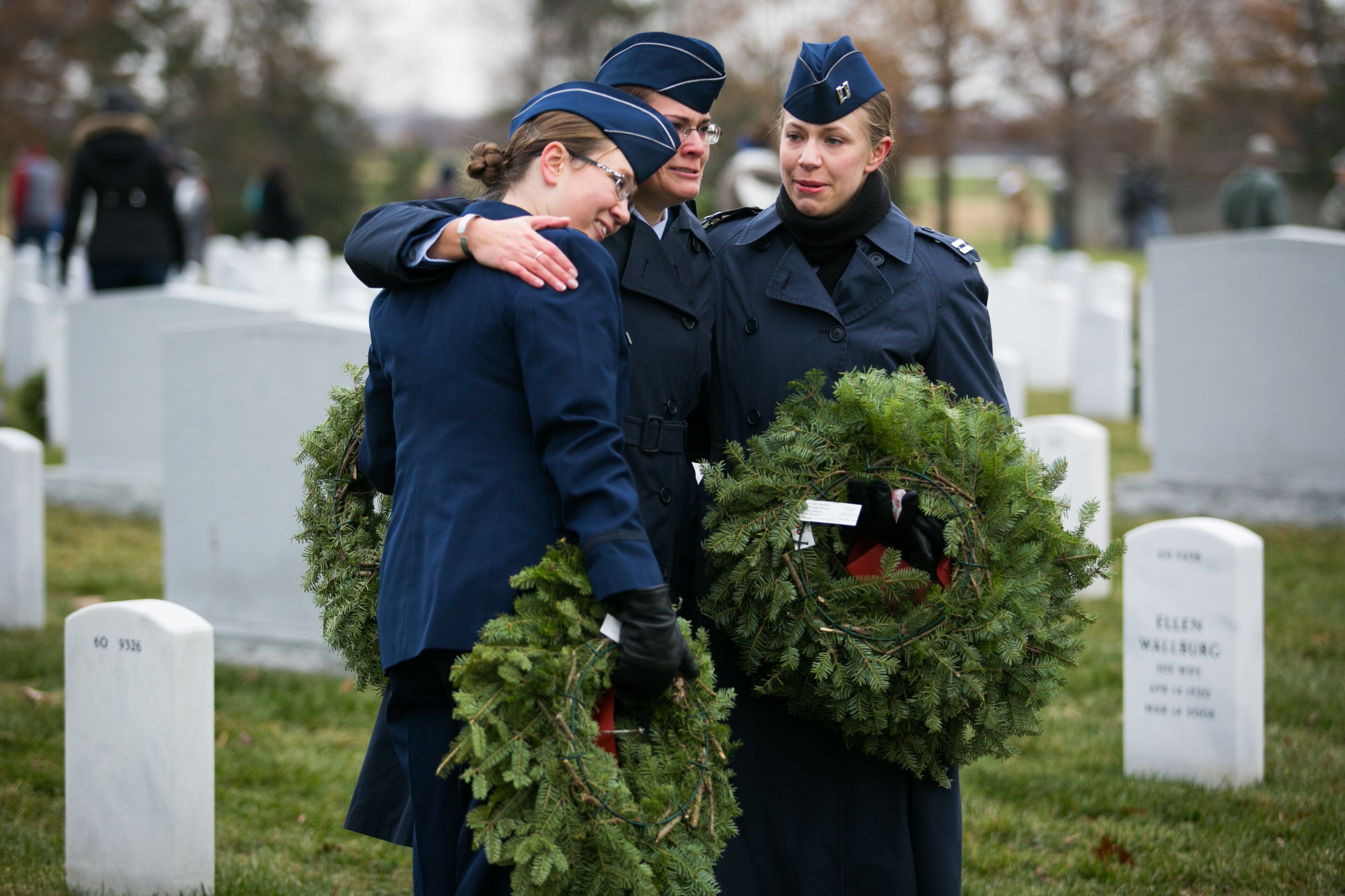ARLINGTON, VA - DECEMBER 14: From L to R, Lt. Maria Hyrczyk, Capt. Jaimie Laib, and Capt. Stephanie Grunzey emrbace in Section 60 of Arlington National Cemetery, December 14, 2013 in Arlington, Virginia. The three are in the U.S. Air Force, stationed at Joint Base Langley-Eustis, and had just layed a wreath at the headstone of their fallen friend Capt. Thomas Graymith. Volunteers and families of the fallen placed thousands of remembrance wreaths on headstones throughout the cemetery on National Wreaths Across America Day. (Photo by Drew Angerer/Getty Images)