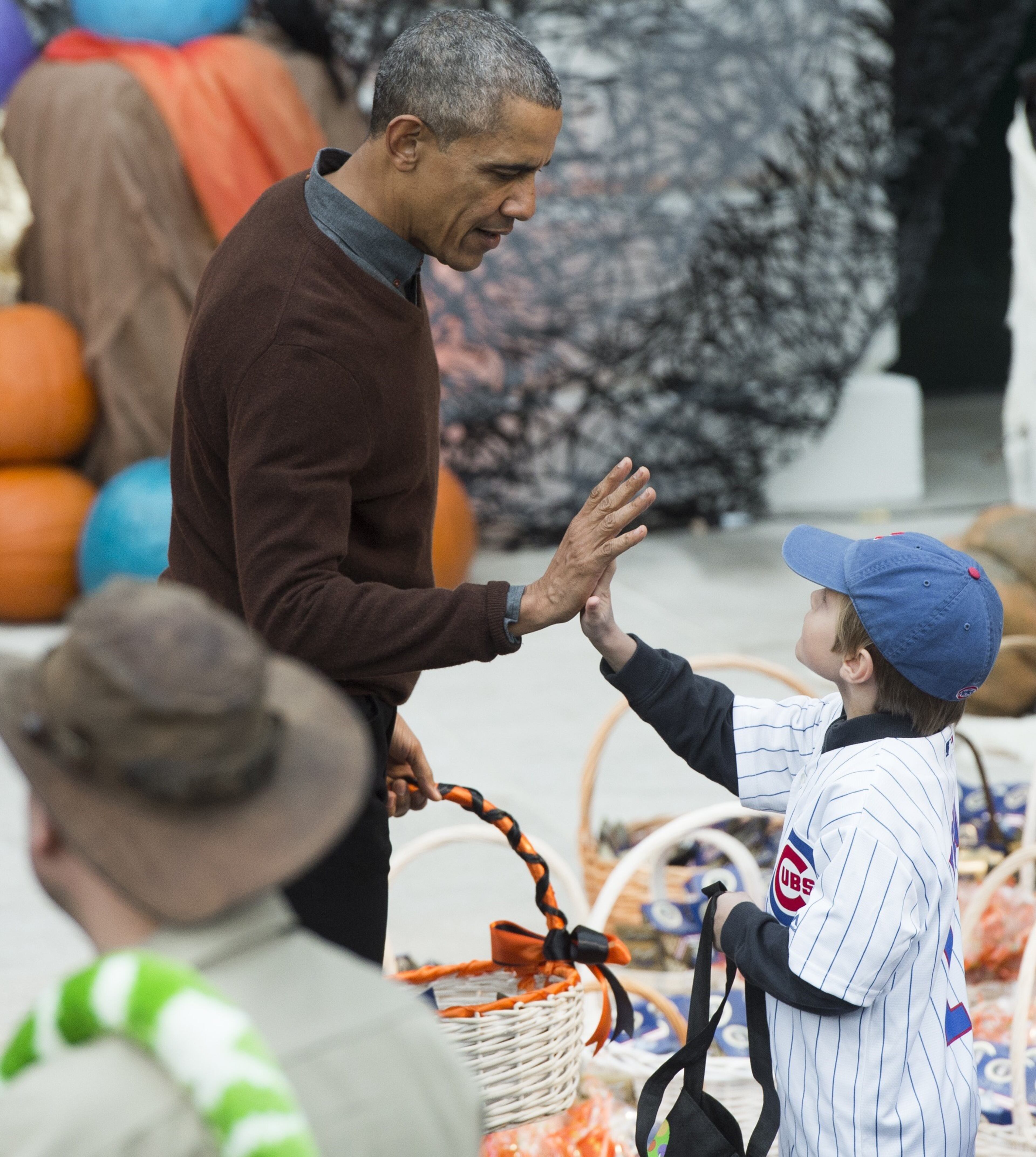 US President Barack Obama high-fives a young boy dressed in a Chicago Cubs uniform as he hands out treats to children trick-or-treating for Halloween on the South Lawn of the White House in Washington, DC, October 30, 2015. AFP PHOTO / SAUL LOEB (Photo credit should read SAUL LOEB/AFP/Getty Images)