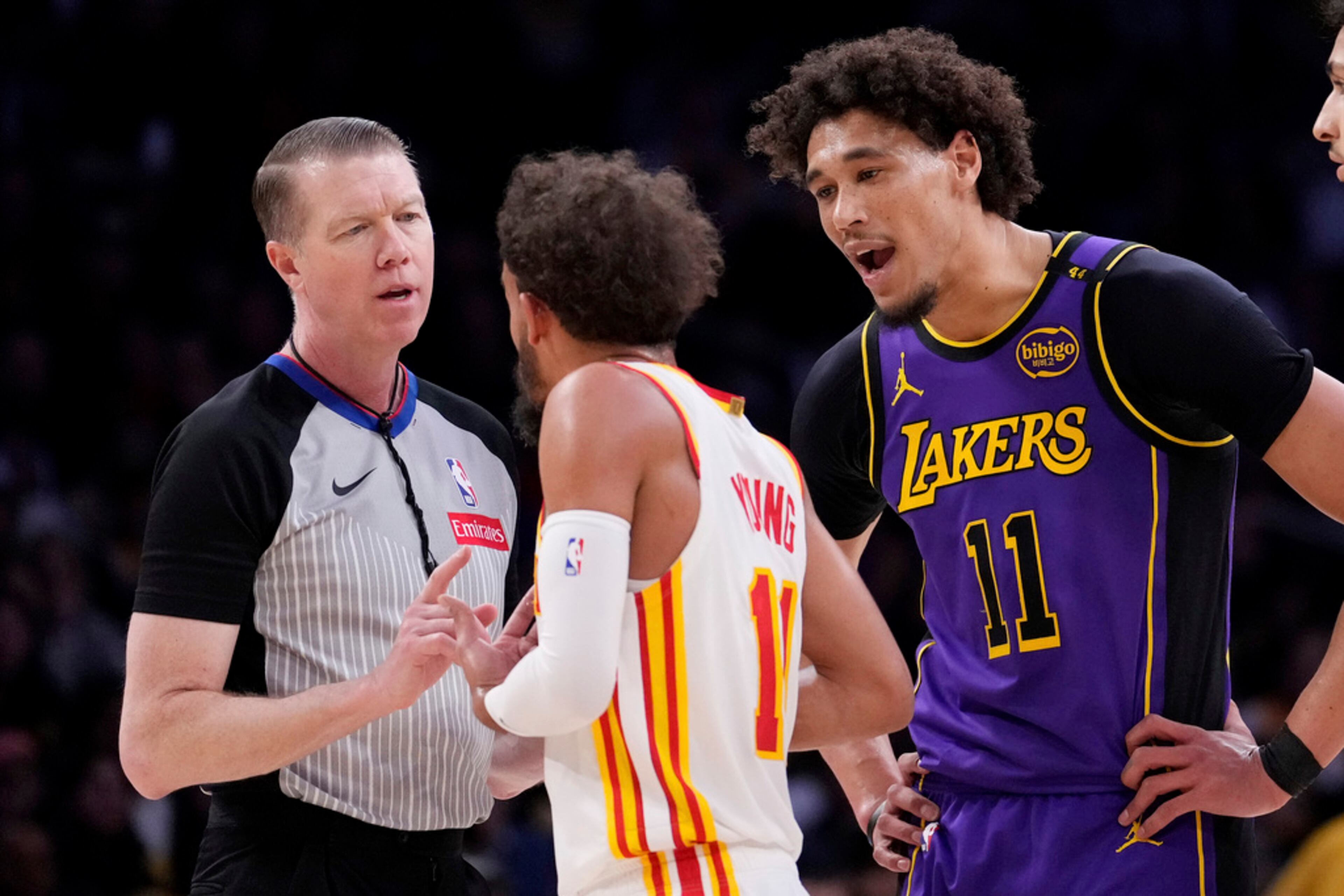Los Angeles Lakers center Jaxson Hayes, right, jaws at Atlanta Hawks guard Trae Young, center, as Young complains to a referee during the first half of an NBA basketball game, Friday, Jan. 3, 2025, in Los Angeles. (AP Photo/Mark J. Terrill)