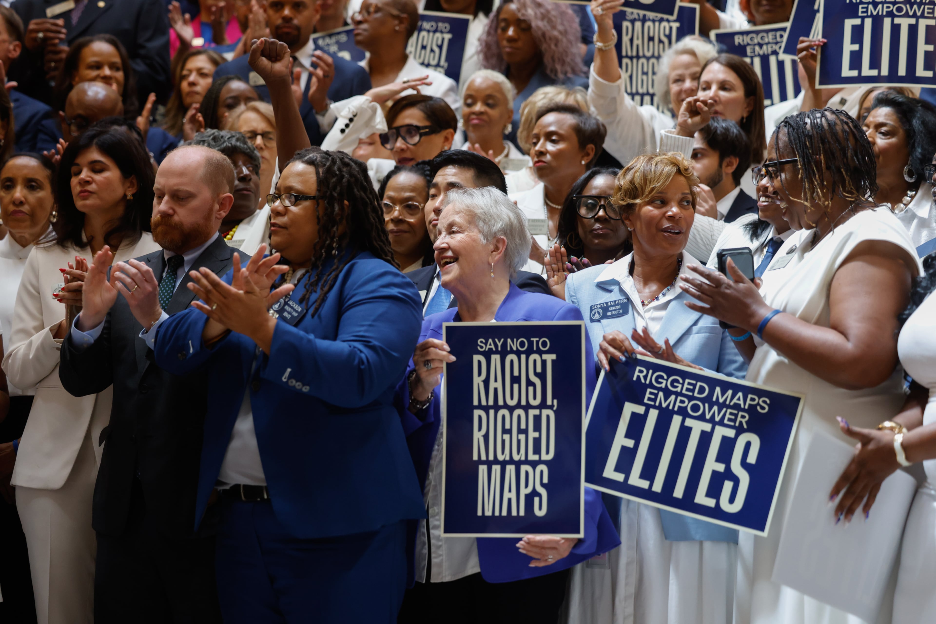 Democratic state representatives and senators, including State Sen. Nan Orrock, D-Atlanta, hold signs opposed to redistricting before the state legislature convenes for a special session in Atlanta on June 17, 2026. (Arvin Temkar/AJC)