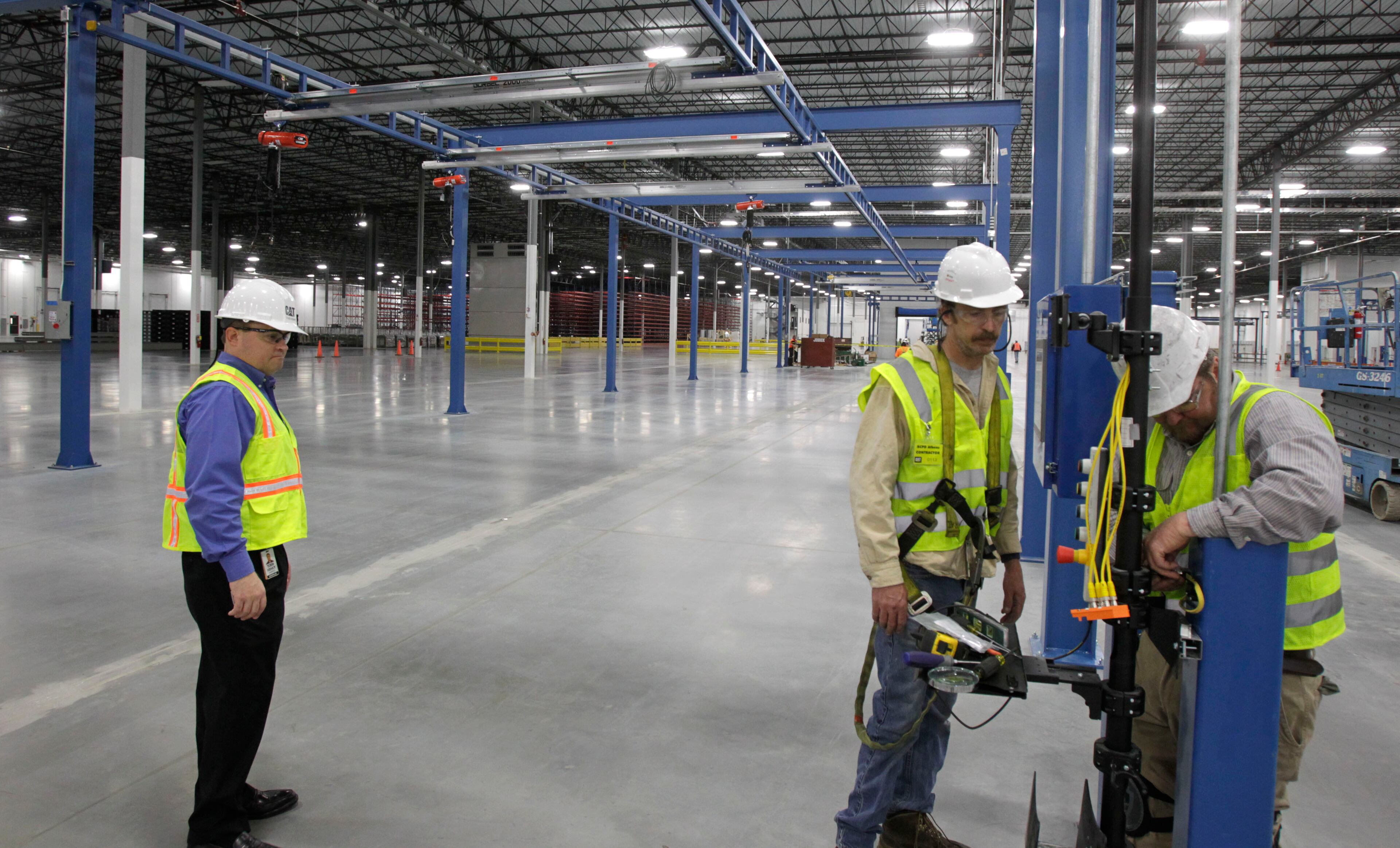 Todd Henry, operations manager (left), watches Jon Pace and Johnny Luthi install communications cabling in the facility. The current 55 employees, with 32 hired from Georgia, are the first of an expected work force of 1,400.