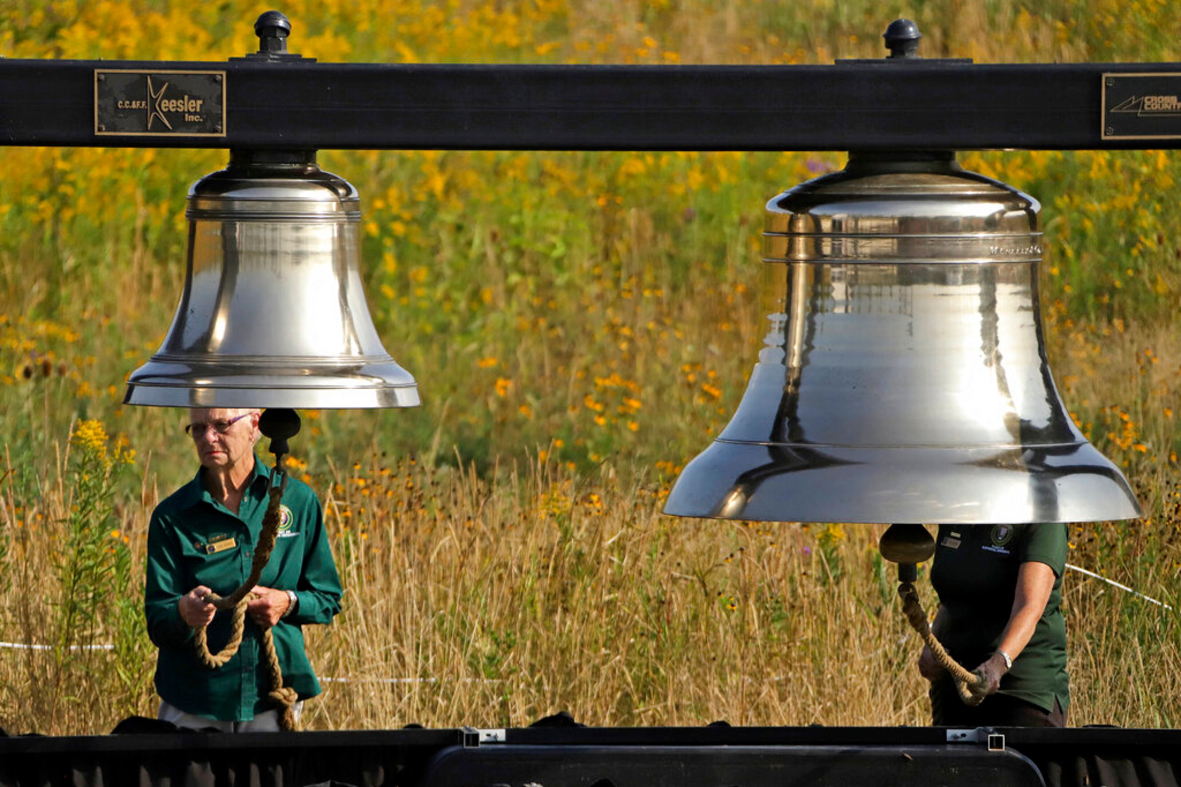 Volunteers Jayne Wagner of Shanksville, Pa., left, and Judy Brant of Indian Lakes, Pa., ring bells as part of the Name Presentation and Ringing of Bells Remembrance of crew and passengers on United Flight 93, during the September 11th Flight 93 Memorial Service in Shanksville, Pa., attended by Vice President Mike Pence, Wednesday, Sept. 11, 2019. (AP Photo/Gene J. Puskar)