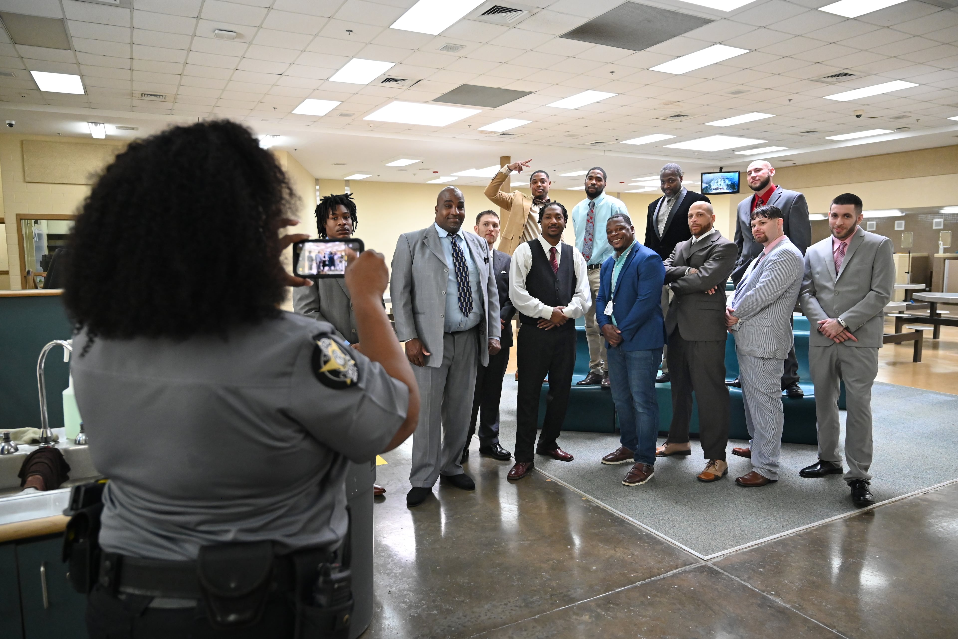Shane Sims (center) poses with graduates as Deputy Gloria Pender (foreground) takes a group photo before their graduation ceremony for the Re-Entry Success Program at the Athens-Clarke County Jail on Wednesday, June 18, 2025, in Athens. (Hyosub Shin/AJC)