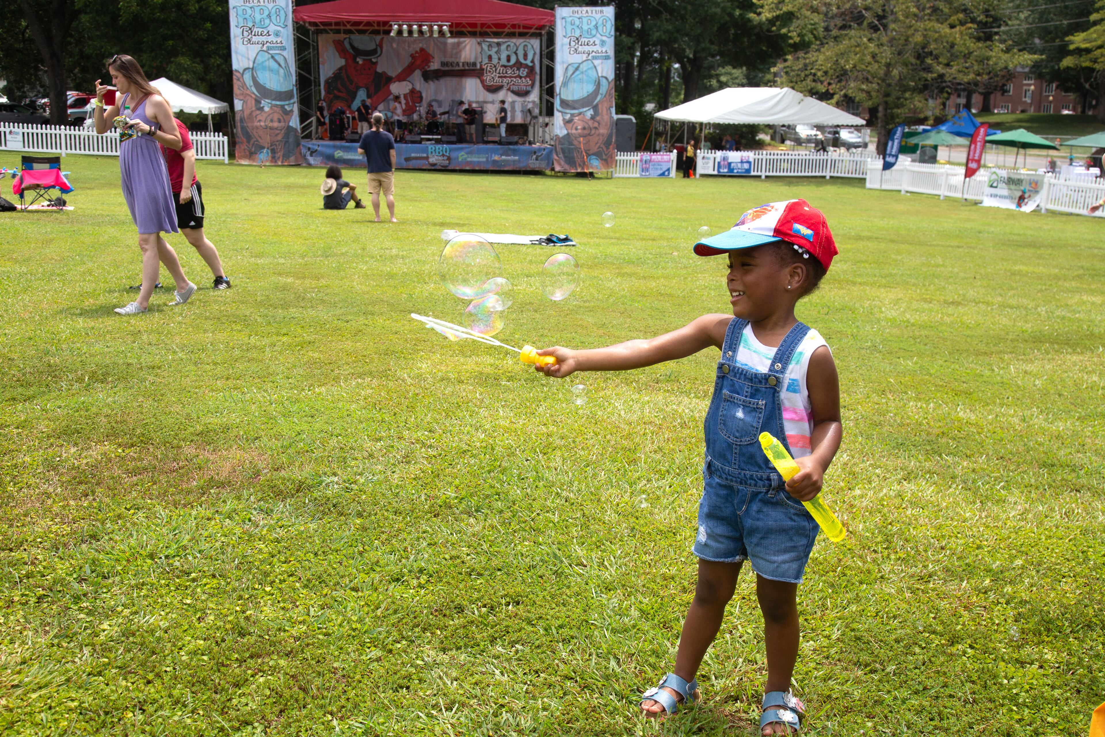 Teagan Richardson makes bubbles before the music starts during the 19th annual Decatur BBQ Blues & Bluegrass festival on Saturday, August 10, 2019. STEVE SCHAEFER / SPECIAL TO THE AJC