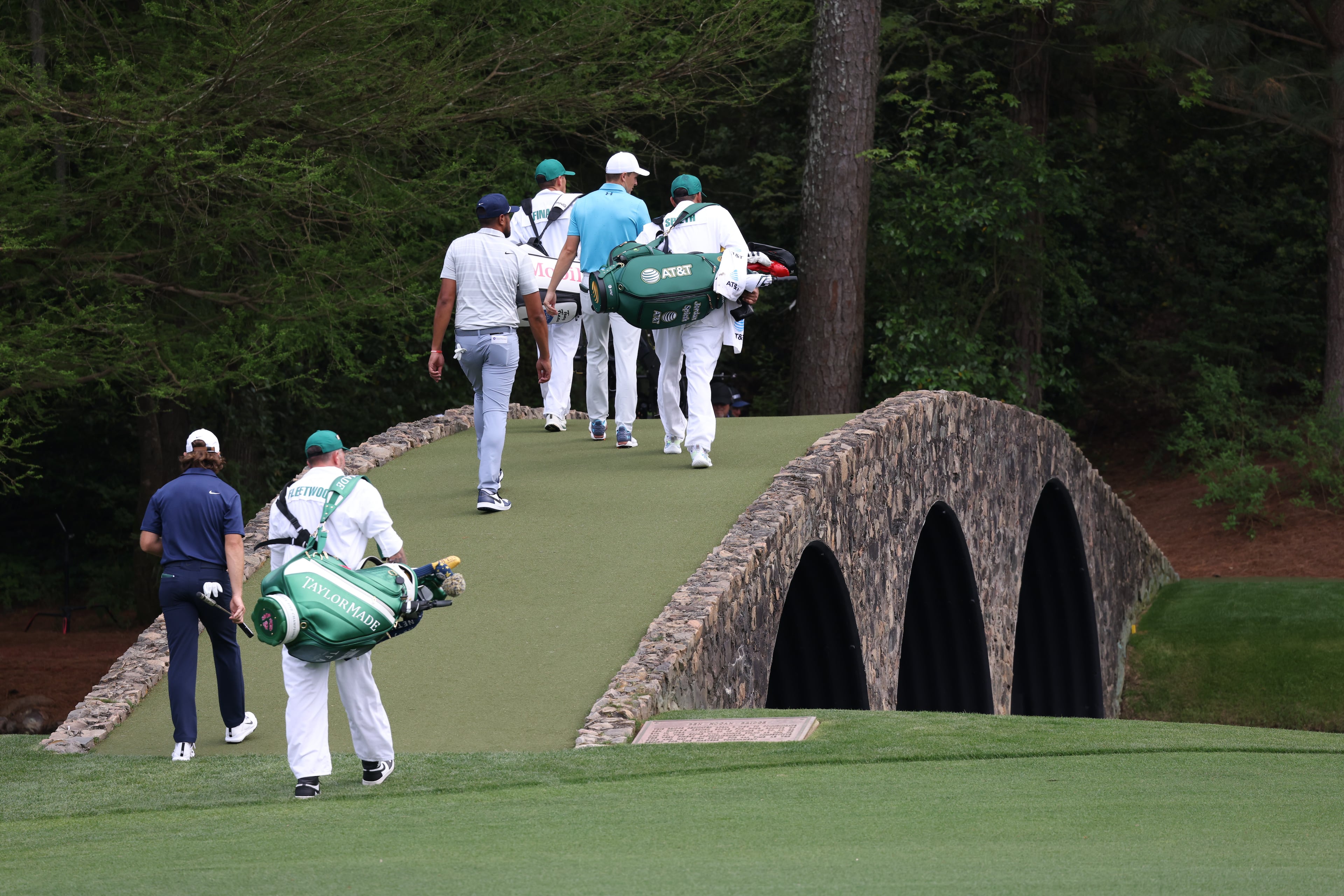 The pairing of Tommy Fleetwood, Tony Finau and Jordan Spieth walk across the bridge on the 13th hole during first round of the 2023 Masters Tournament at Augusta National Golf Club, Thursday, April 6, 2023, in Augusta, Ga. (Jason Getz / Jason.Getz@ajc.com)
