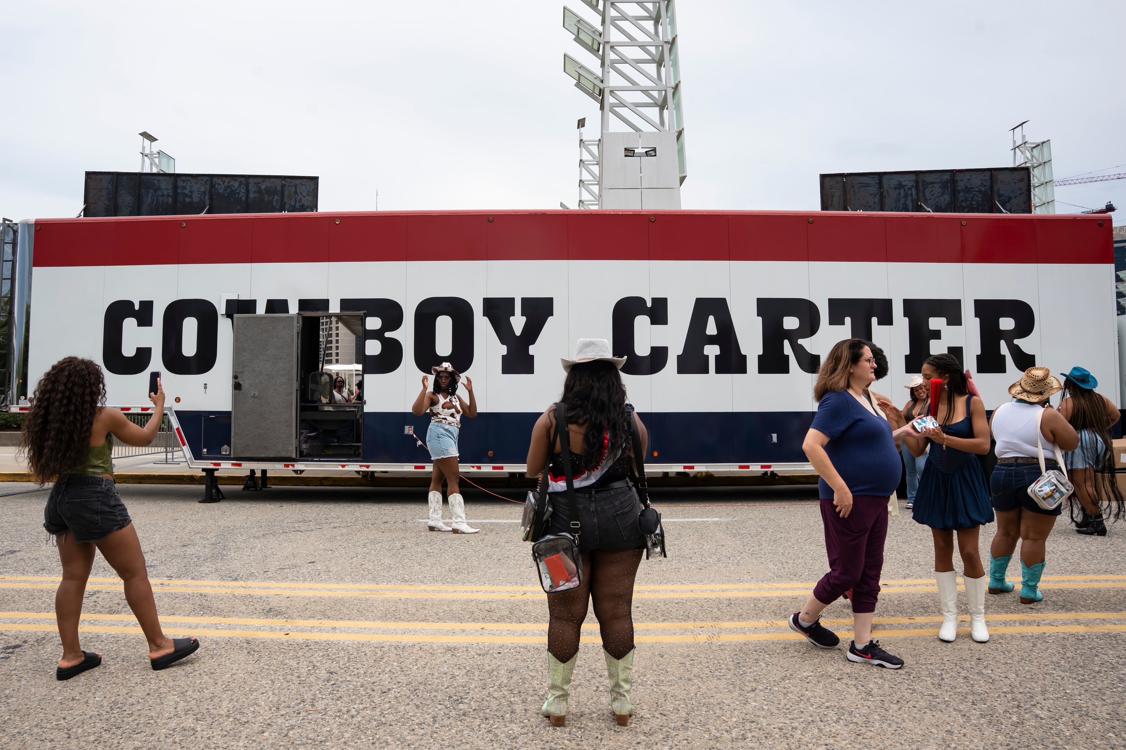 Fans pose in front of the Cowboy Carter merch sign in line outside Beyoncé's concert in Atlanta on Thursday, July 10, 2025. (Olivia Bowdoin for the AJC)