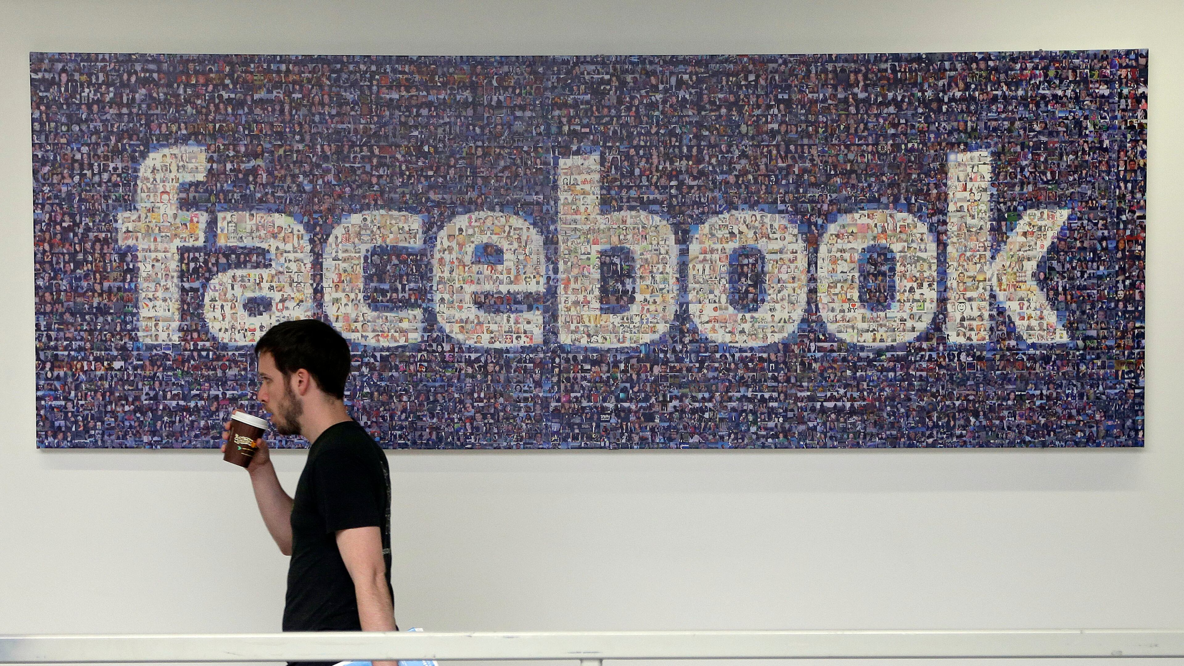 FILE - In this March 15, 2013, file photo, a Facebook employee walks past a sign at Facebook headquarters in Menlo Park, Calif. Facebook reports financial results on Wednesday, April 27, 2016. (AP Photo/Jeff Chiu, File)