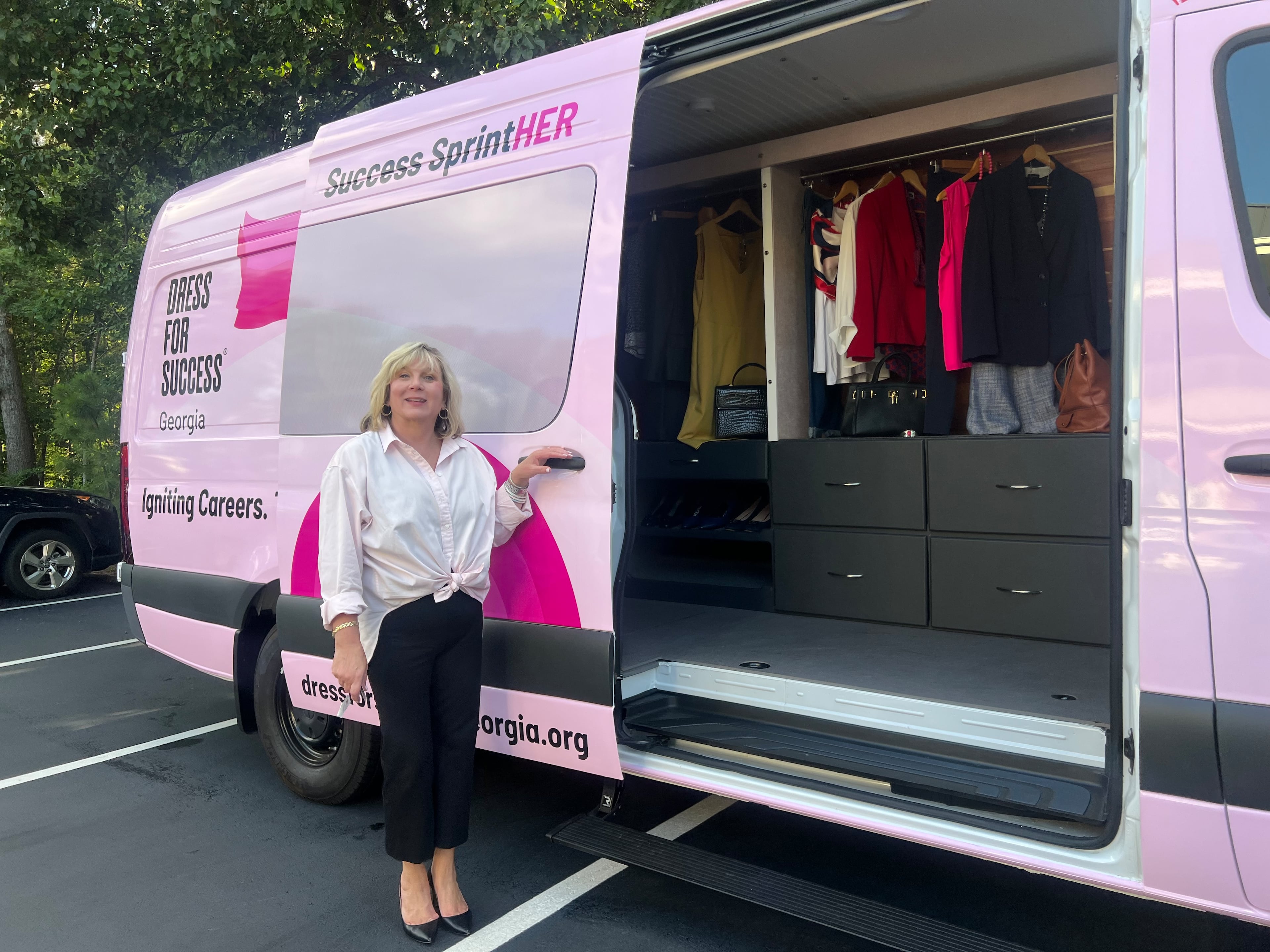 Susan Bonds-McCulloch, president of Dress for Success Georgia, stands in front of the organization’s Success SprintHER van. The van has a mobile career and workforce development center, along with a professional clothing closet and dressing room. (Kelly Yamanouchi/AJC)