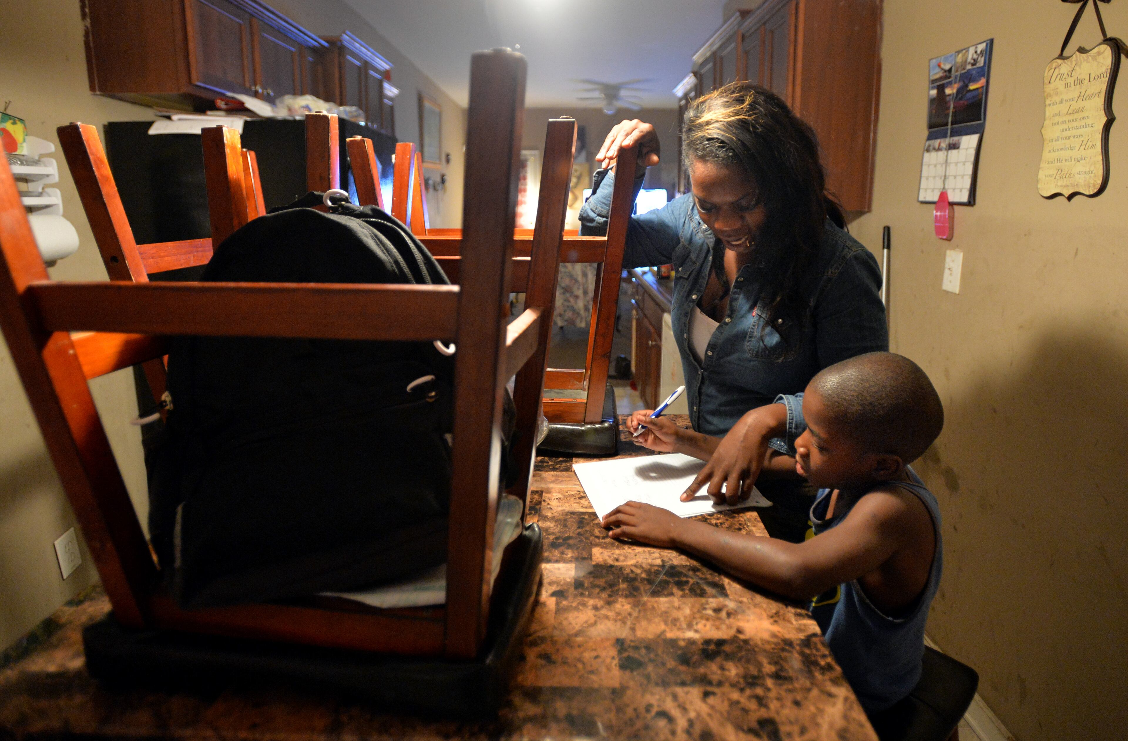 Ashley Roberson, 23, helps her younger brother Damyuss Marshall, 8, with his homework. HYOSUB SHIN / HSHIN@AJC.COM