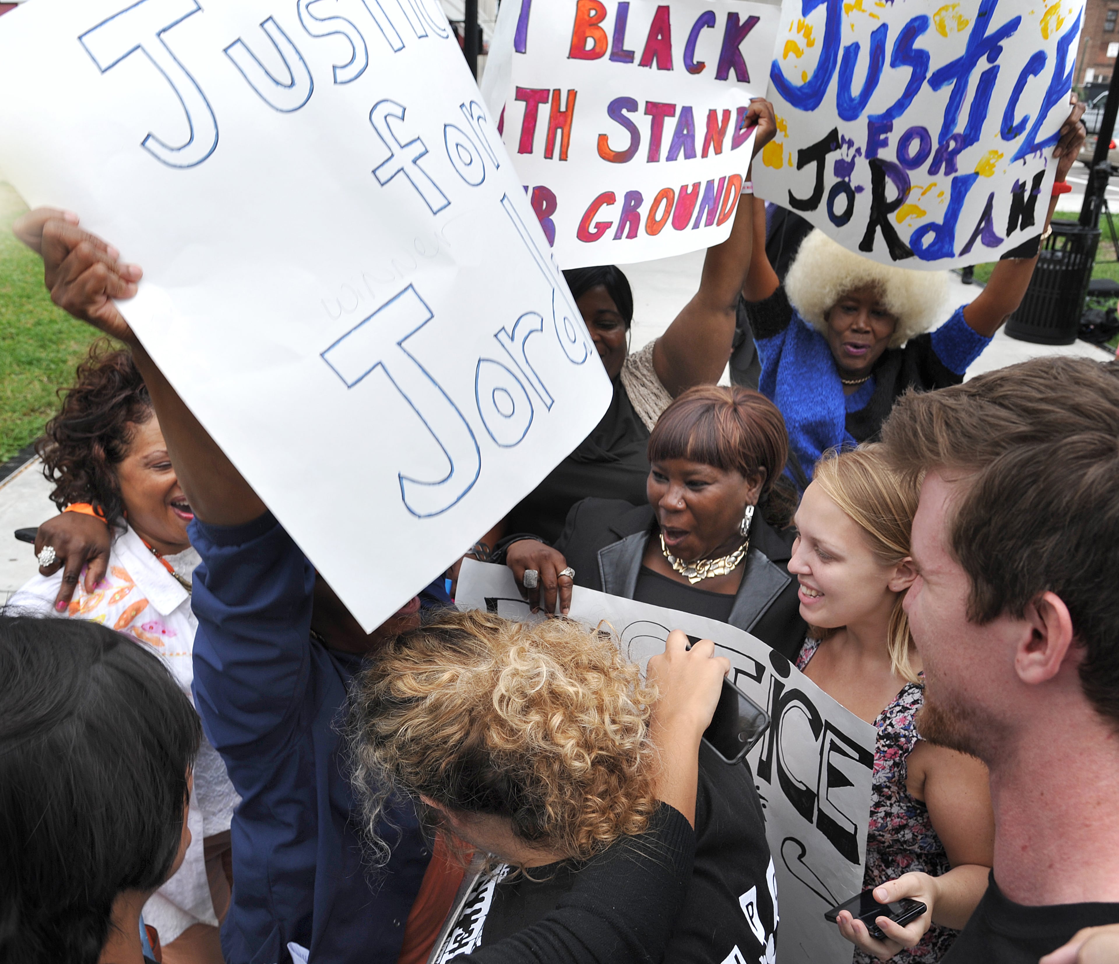 Members of the Jacksonville Progressive Coalition share a group hug outside of the Duval County Courthouse on Wednesday, Oct. 1, 2014 in Jacksonville, Fla., after a jury convicted Micheal Dunn of first-degree murder in his retrial for killing teenager Jordan Davis after an argument over loud music. (AP Photo/The Florida Times-Union, Bruce Lipsky)