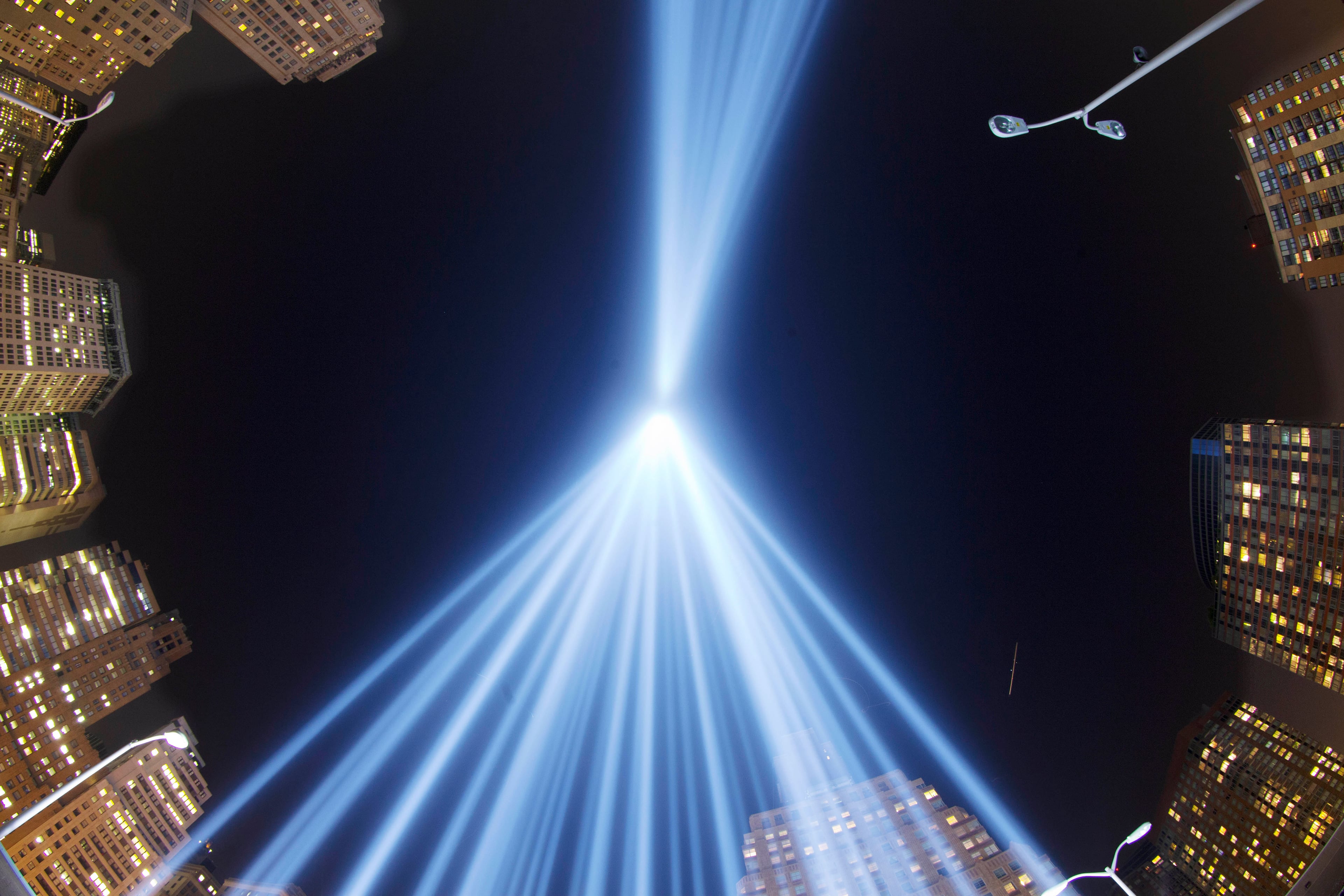 In a photo made with a fisheye lens, the Tribute in Light rises above buildings in lower Manhattan, during a test, Tuesday, Sept. 10, 2013 in New York. The light display commemorates the twin towers of the World Trade Center that were destroyed in terrorist attacks 12 years ago on Sept. 11, 2001. (AP Photo/Mark Lennihan)