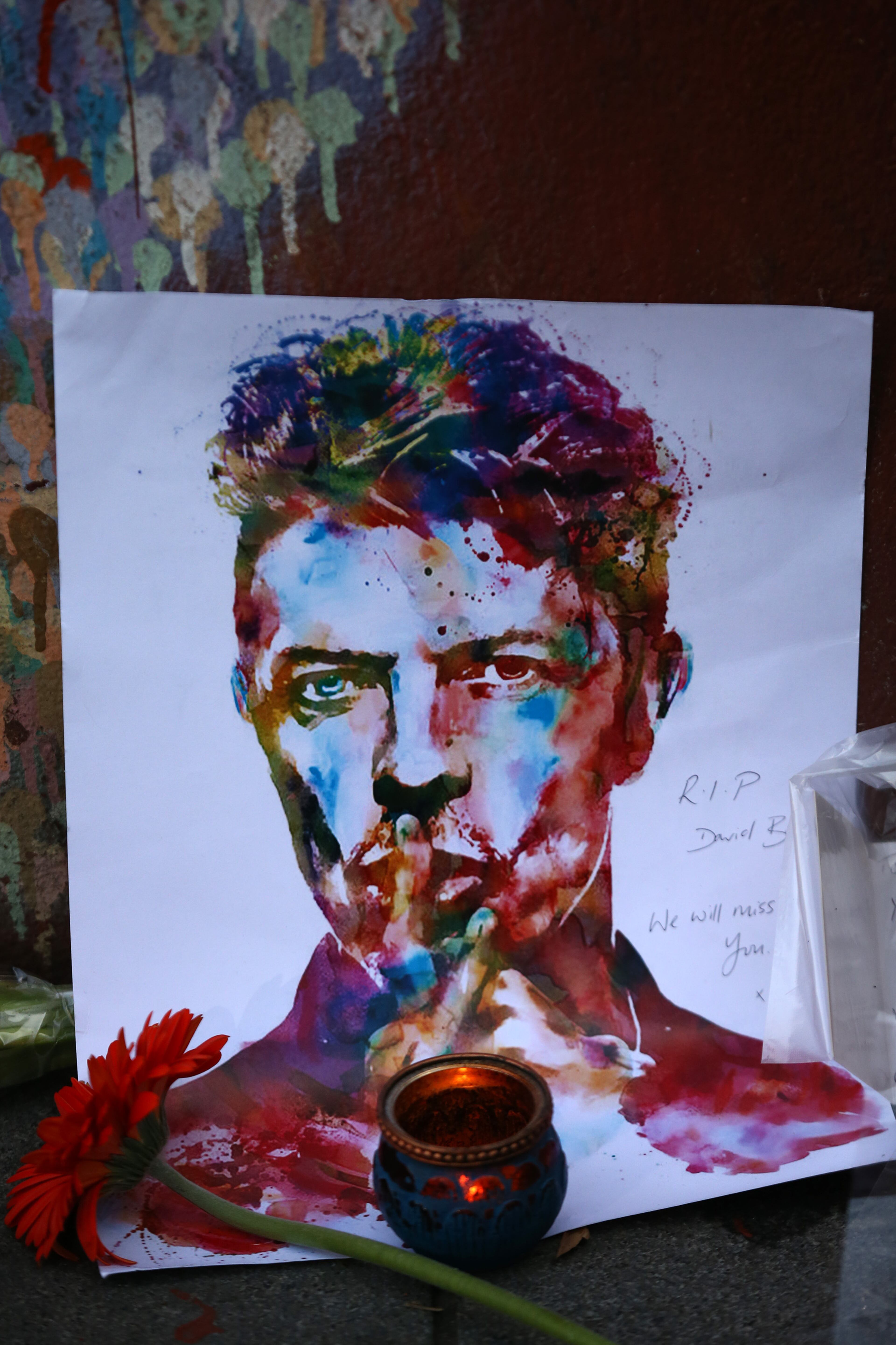 LONDON, ENGLAND - JANUARY 11: A message, picture and flower are left beneath a mural of David Bowie in Brixton on January 11, 2016 in London, England. British music and fashion icon David Bowie died earlier today at the age of 69 after a battle with cancer. (Photo by Carl Court/Getty Images)